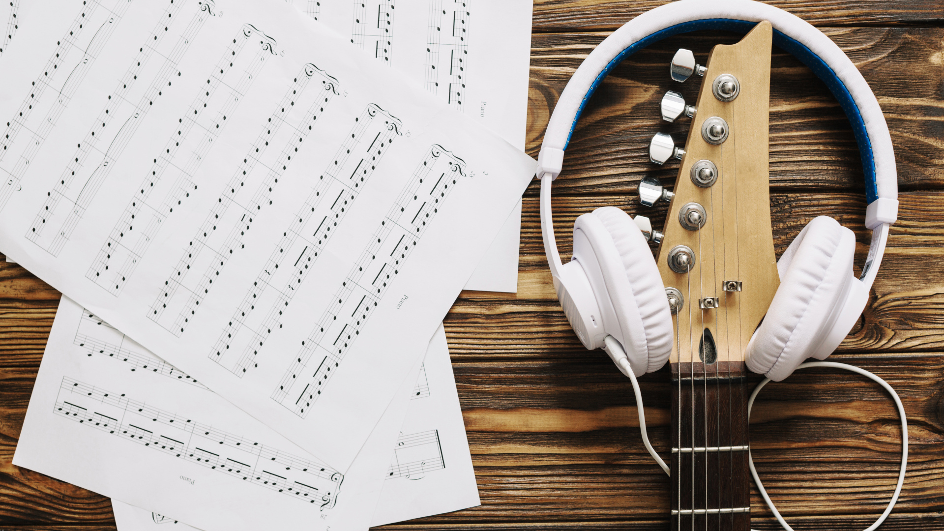 Ноты, наушники и гитара на столе