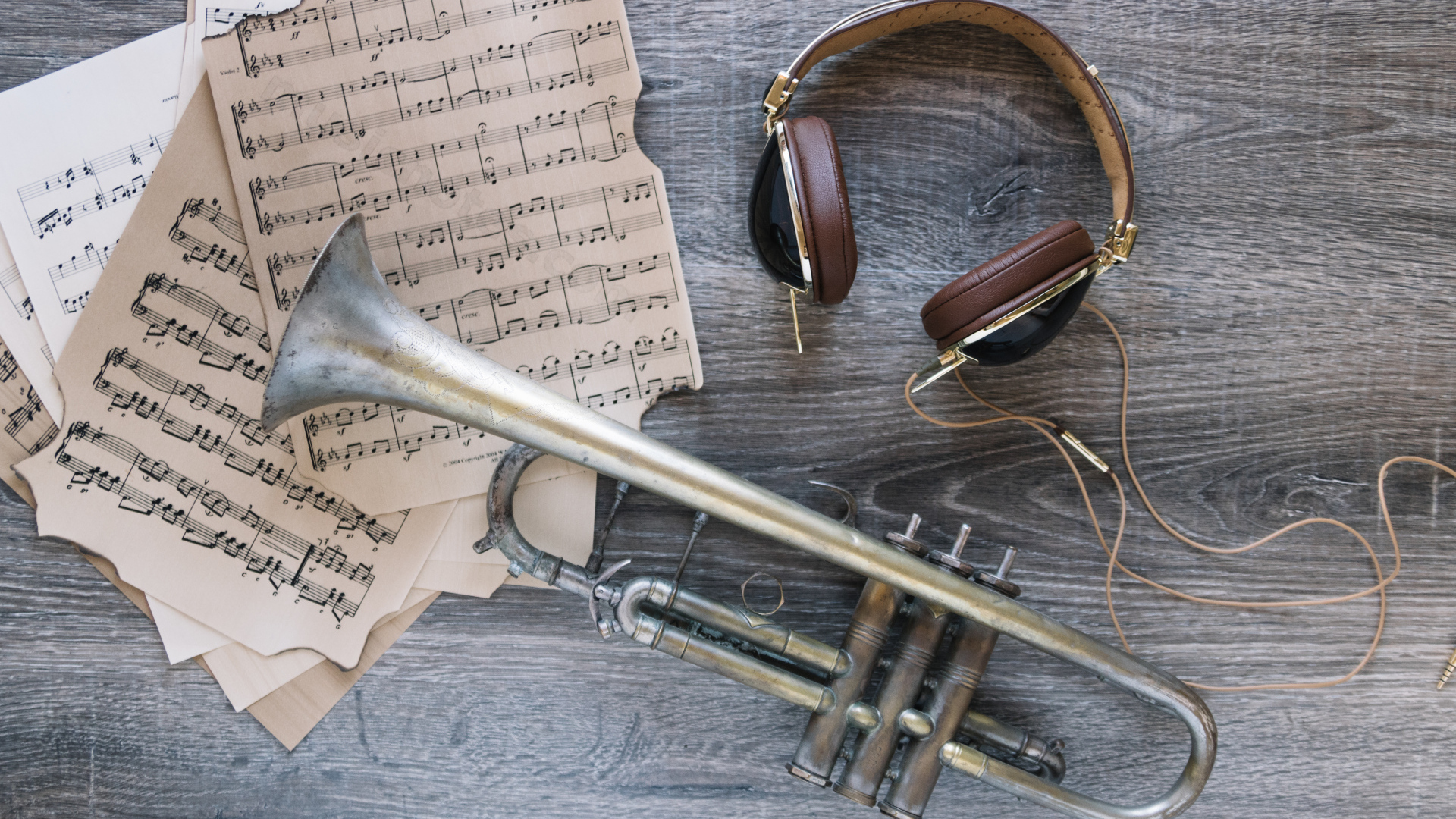 Старые ноты, наушники и труба на столе