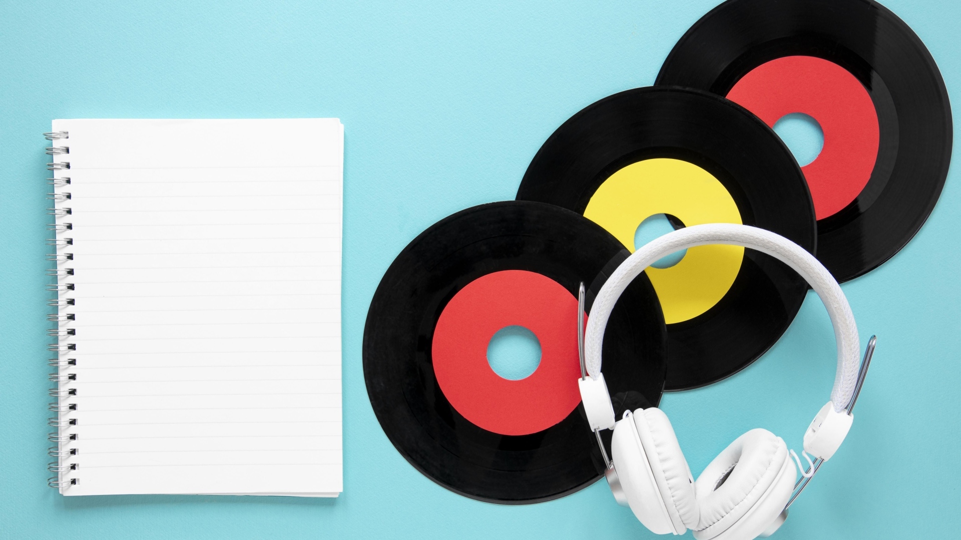Пластинки на голубом фоне с блокнотом и наушниками