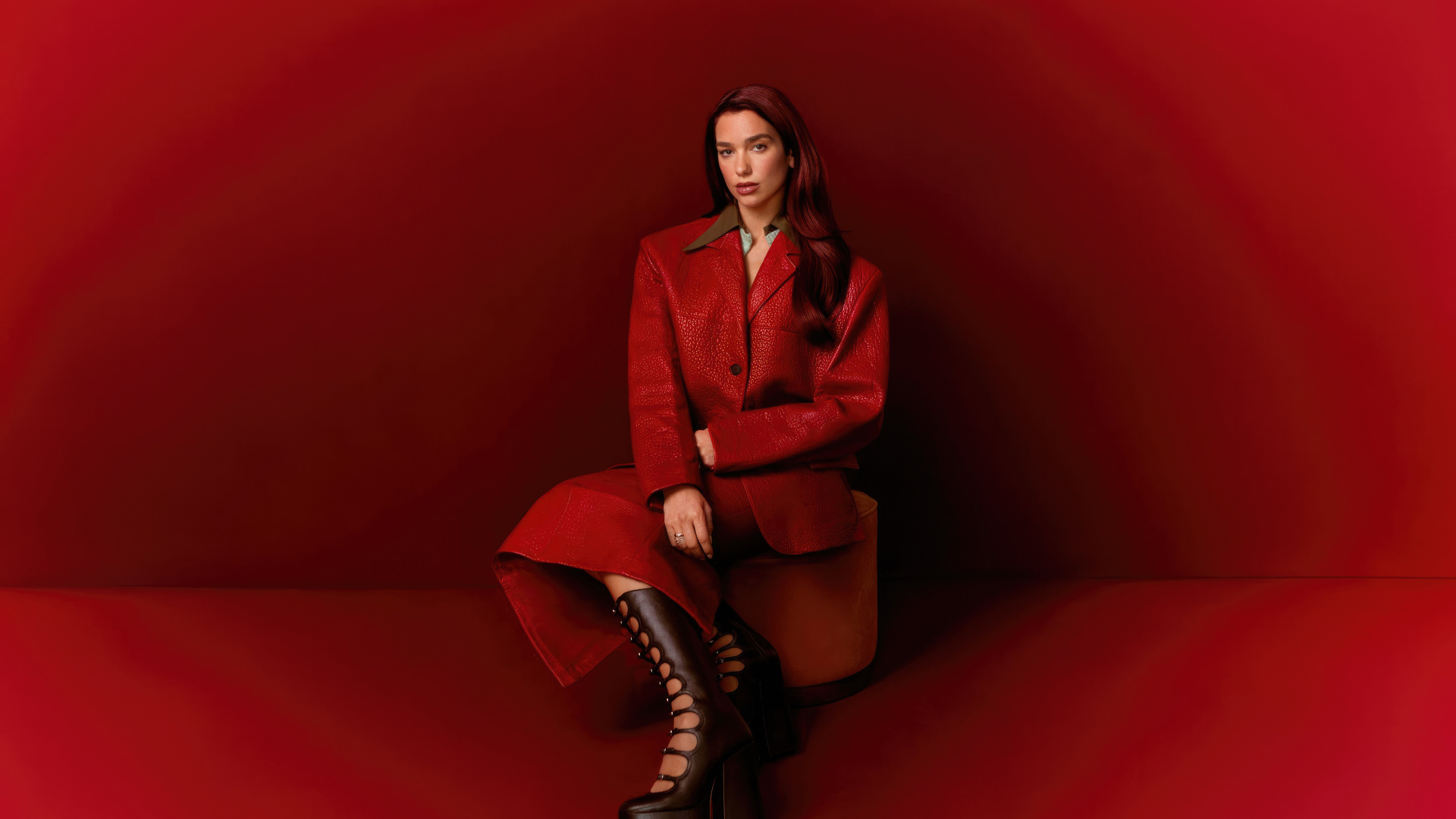 Певица Дуа Липа позирует на красном фоне
