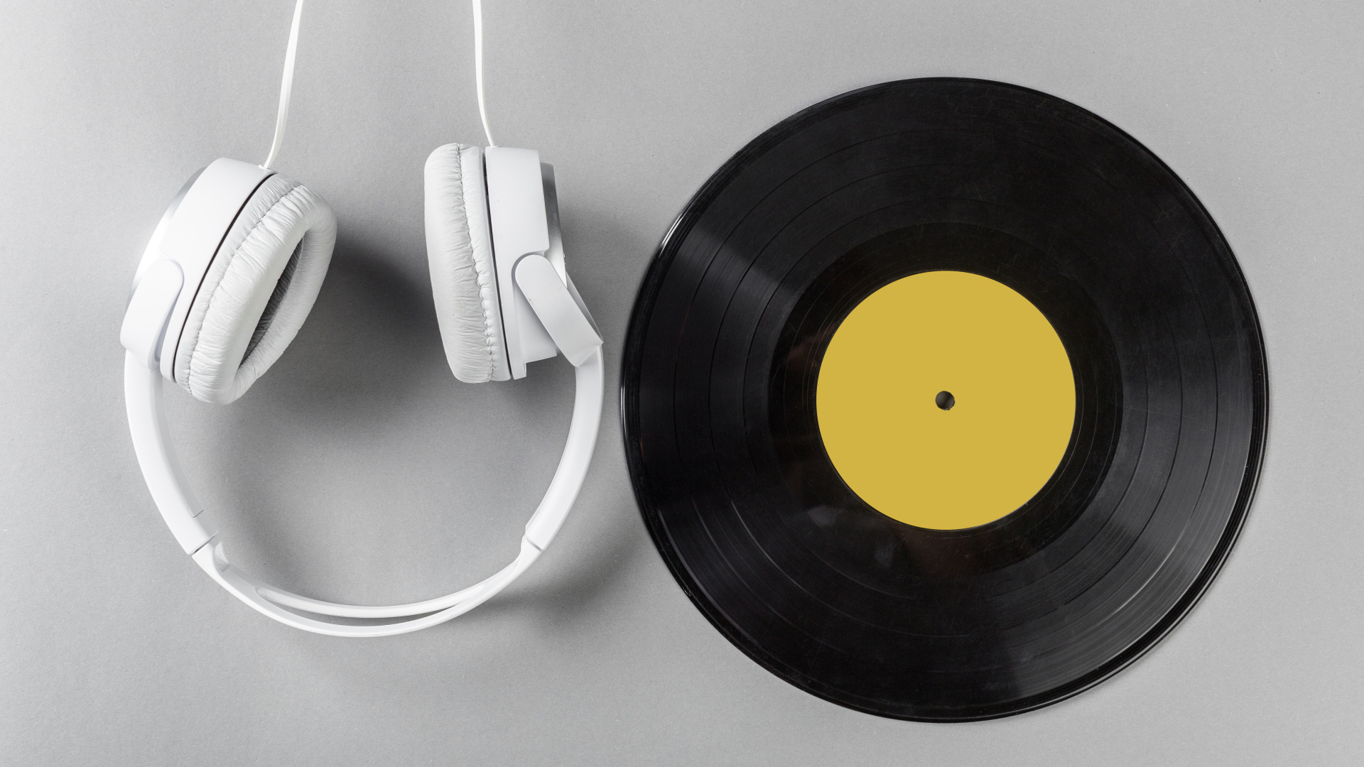 Виниловая пластинка и наушники на сером столе