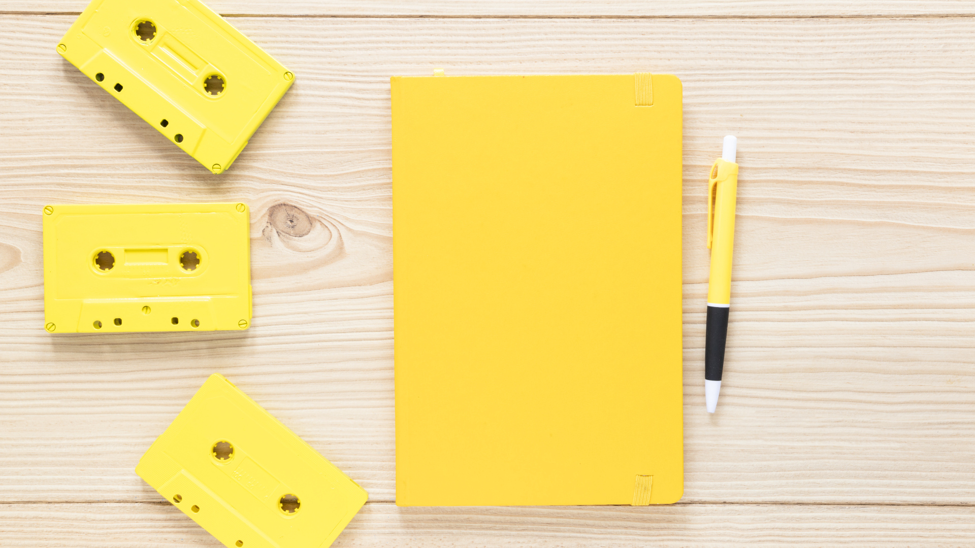 Желтый блокнот с ручкой и кассетами на столе