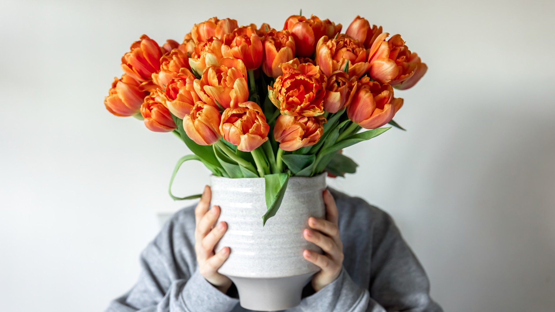 Букет оранжевых тюльпанов в вазе в руках