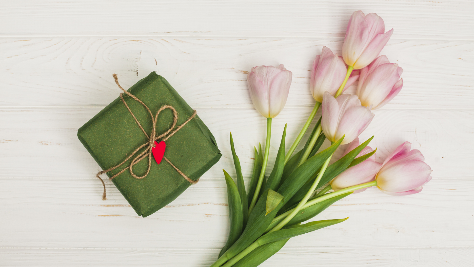 Букет розовых тюльпанов на столе с подарком