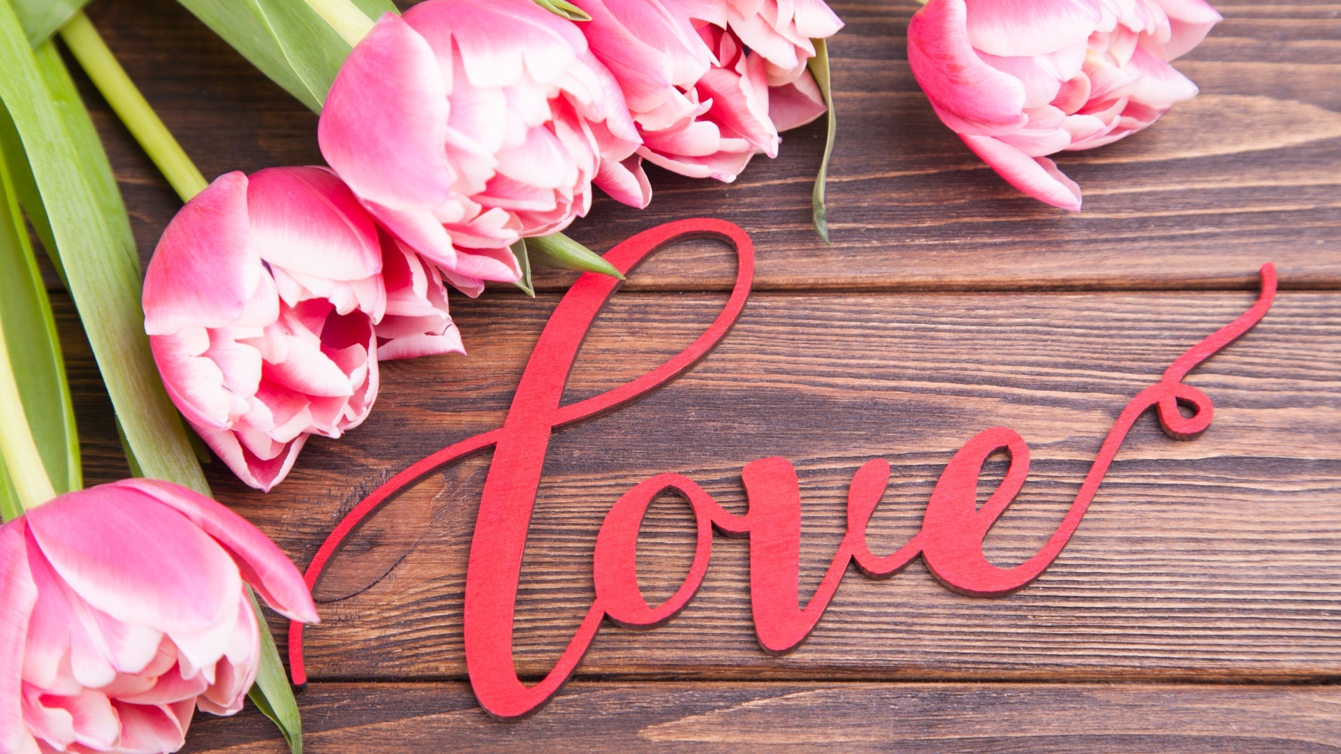 Букет розовых тюльпанов с надписью любовь на деревянном столе