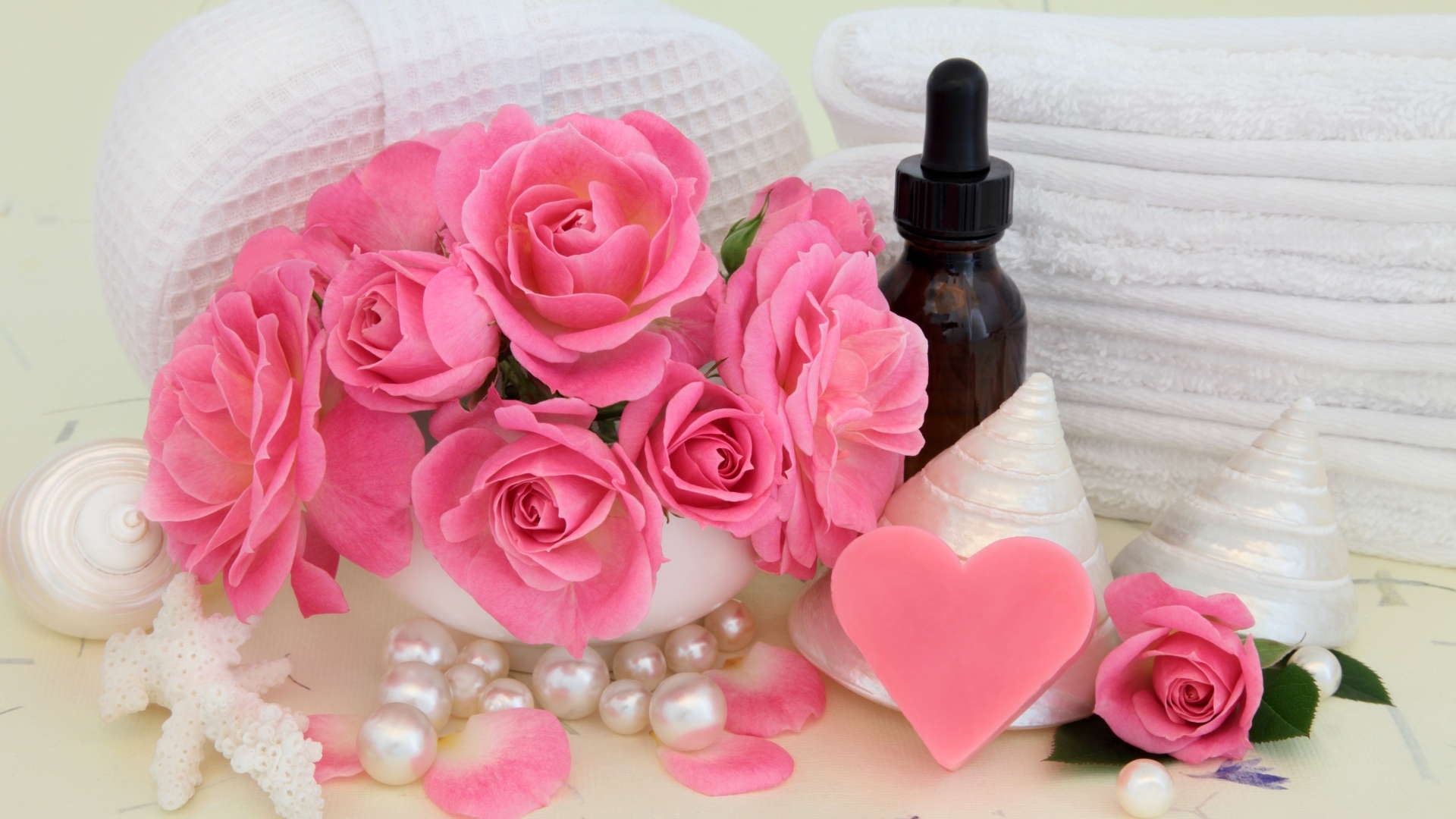 Розовые розы с полотенцами, ракушками и маслом на столе