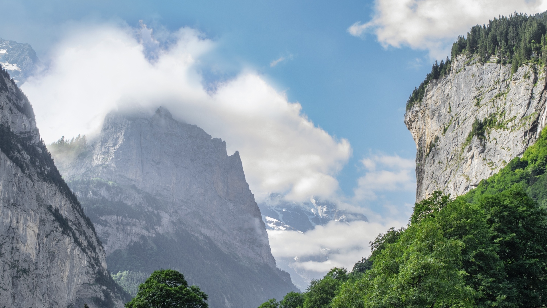 Высокие покрытые зеленью горы в белых облаках