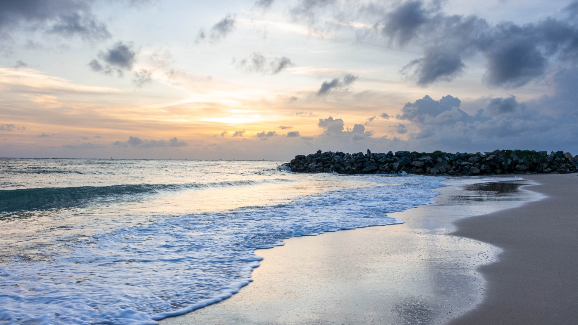 Волны омывают морской песок на рассвете