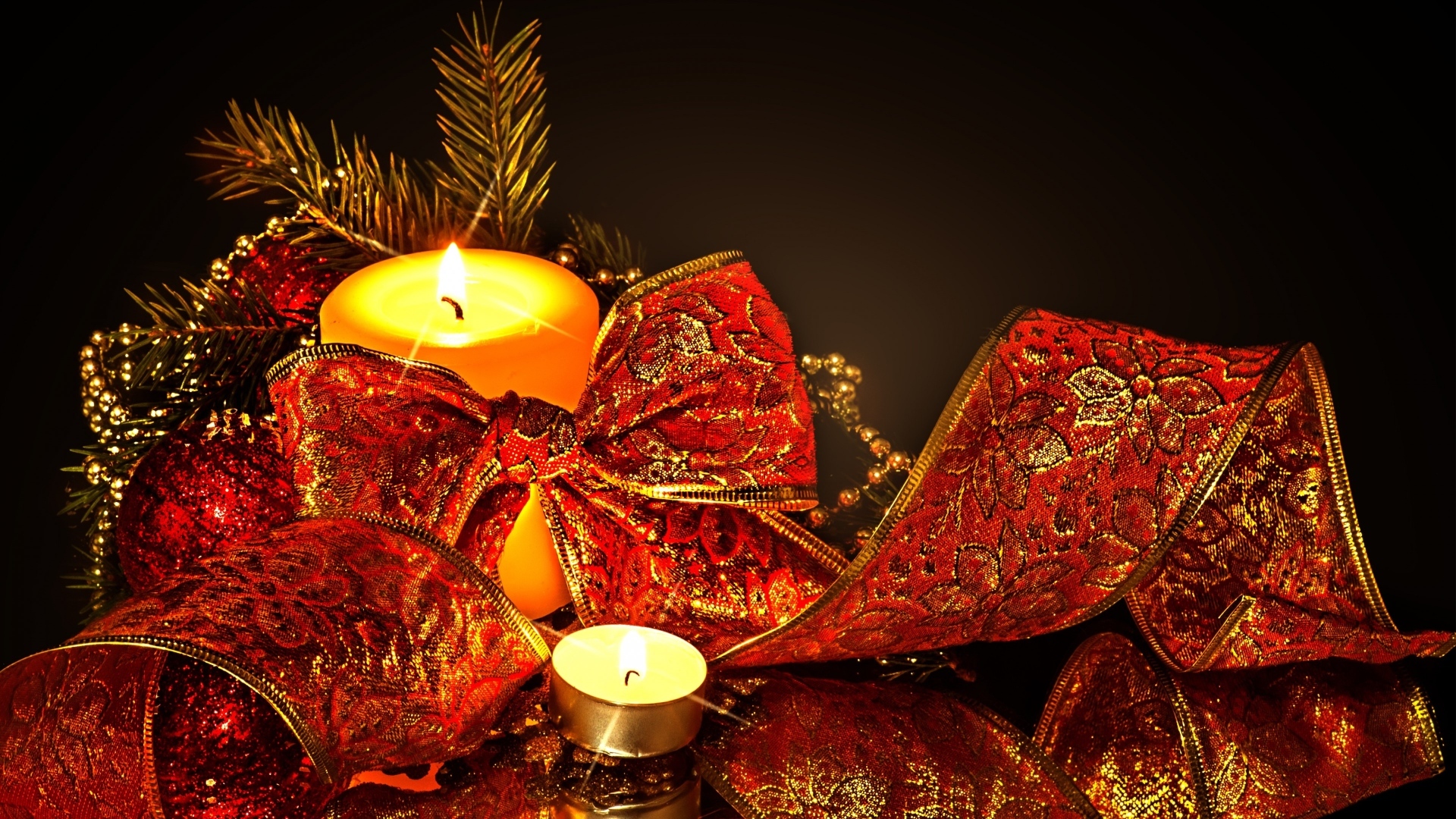 Зажженная свеча с красным бантом на черном фоне на Новый год