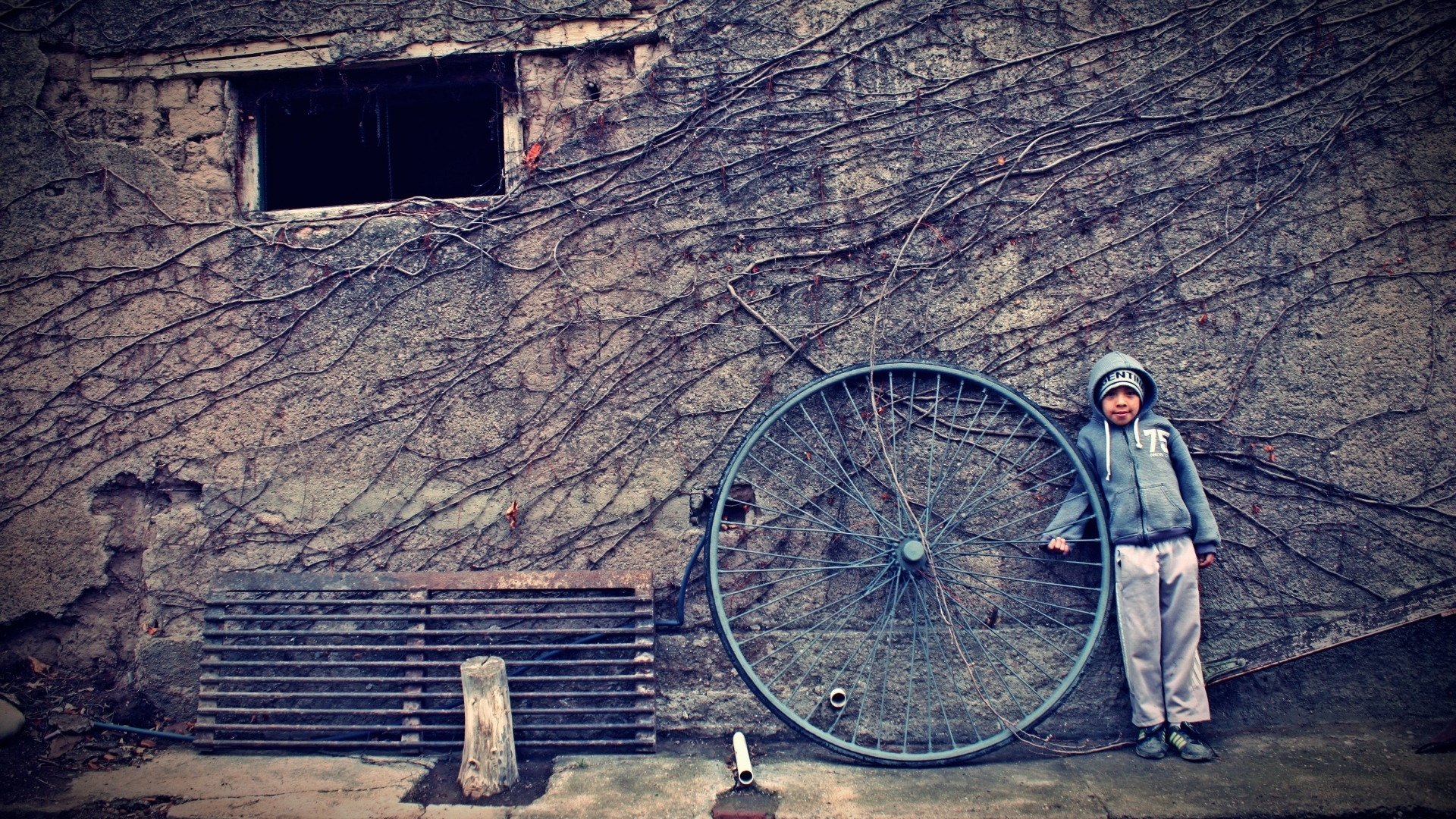 Мальчик с большим колесом стоит у стены