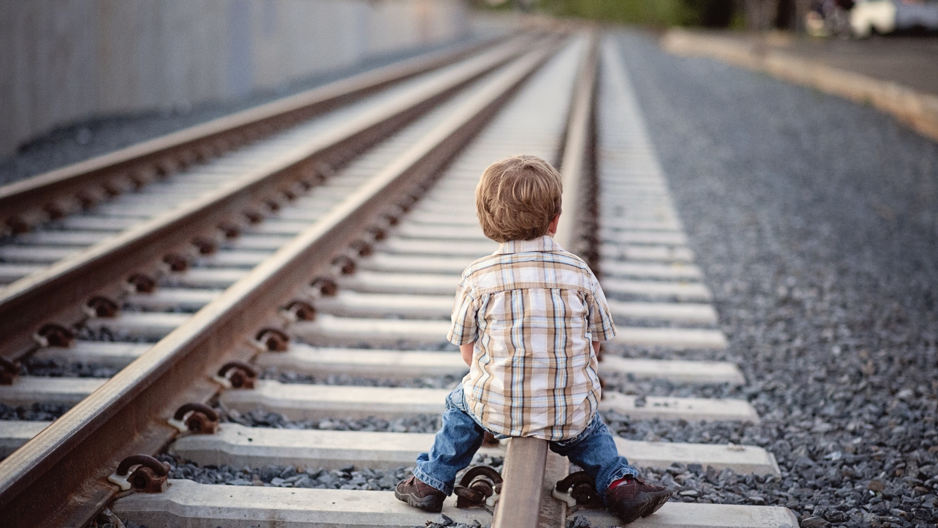 Мальчик сидит на железнодорожных рельсах