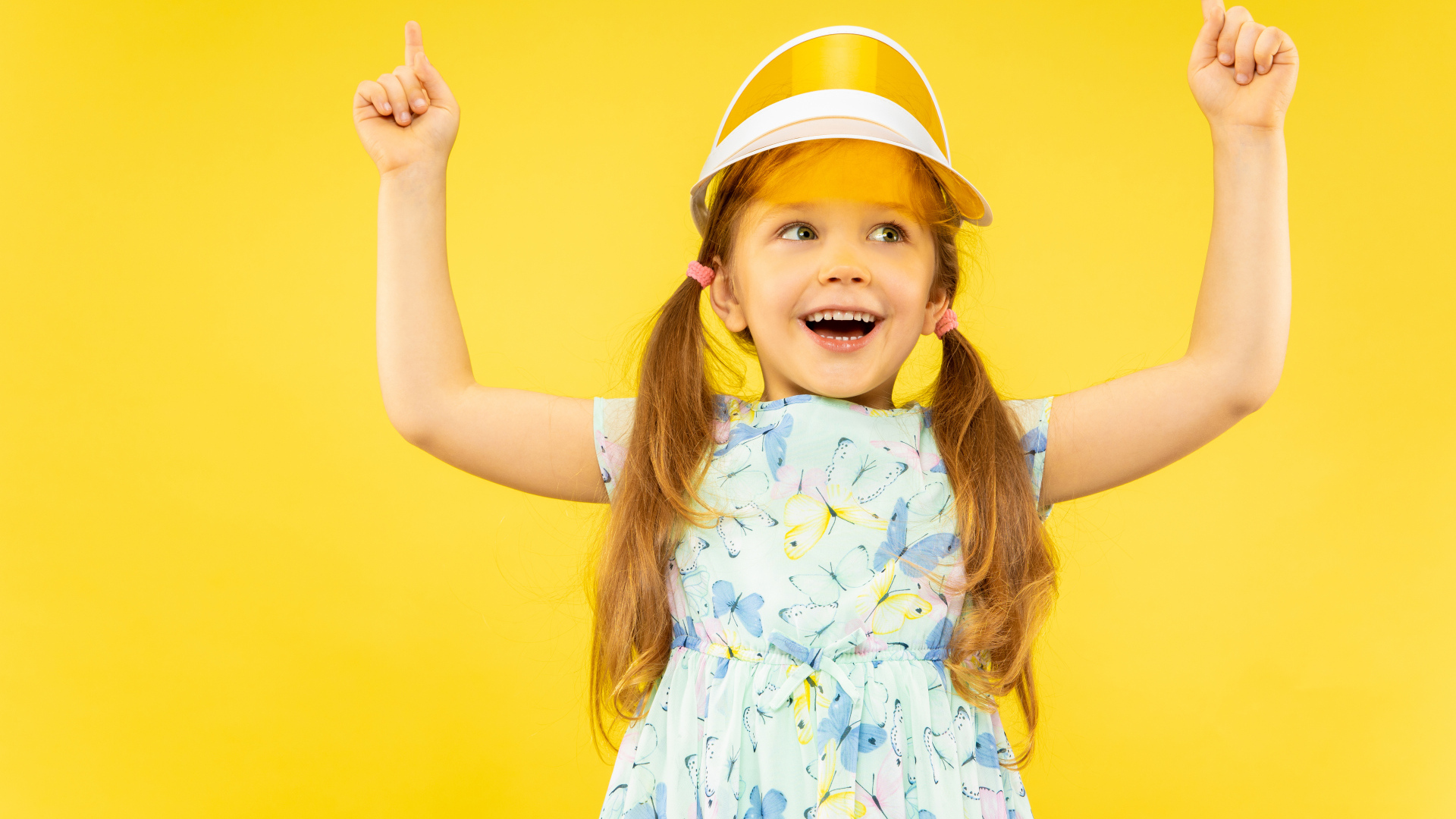 Веселая девочка в платье на желтом фоне