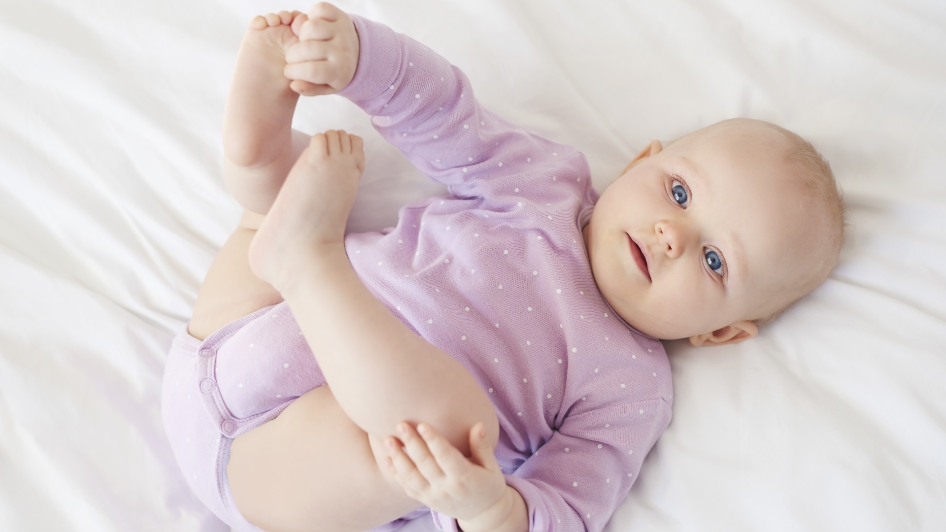 Милый голубоглазый малыш на белом покрывале