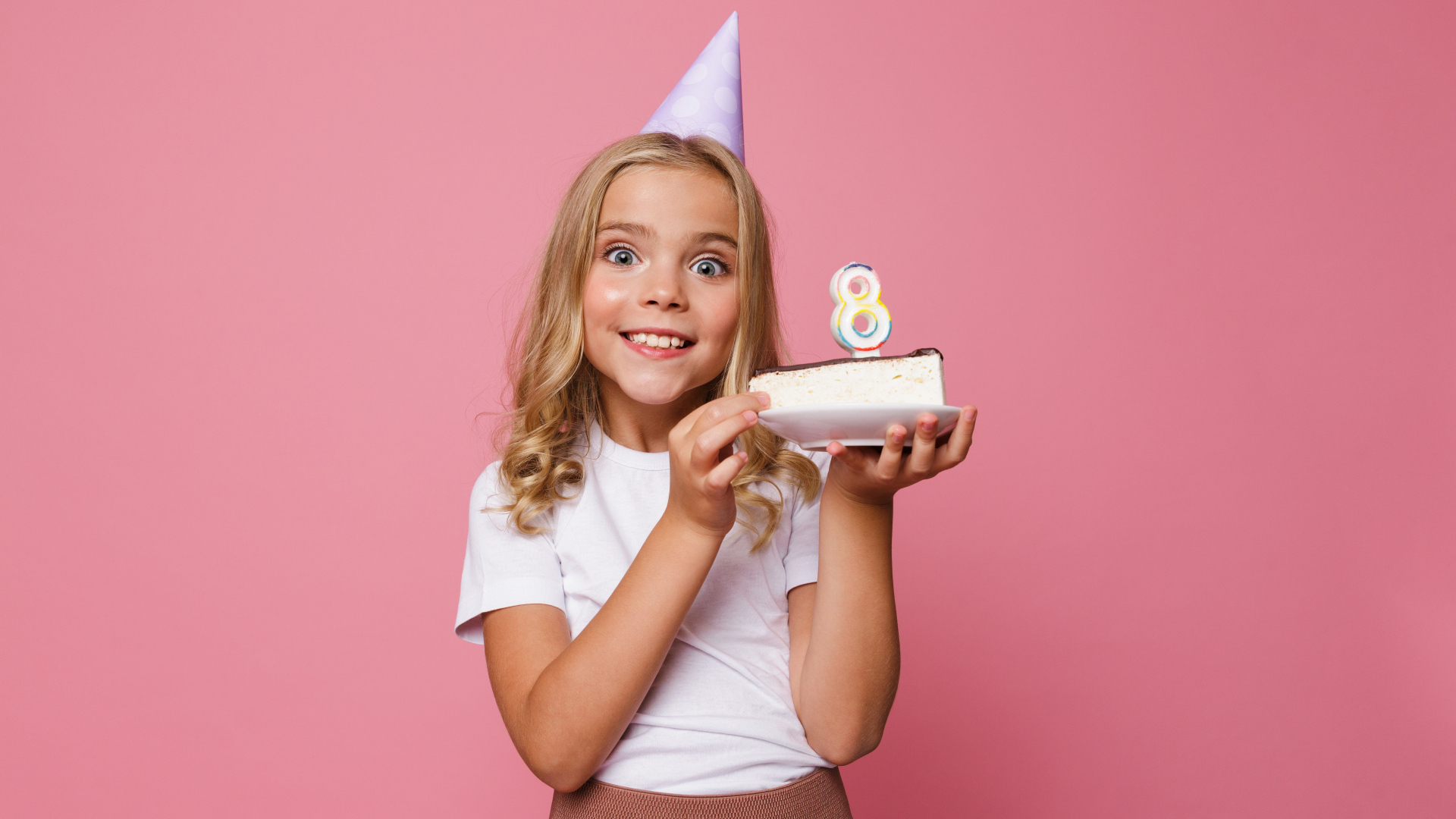 Милая девочка отмечает день рождения на розовом фоне