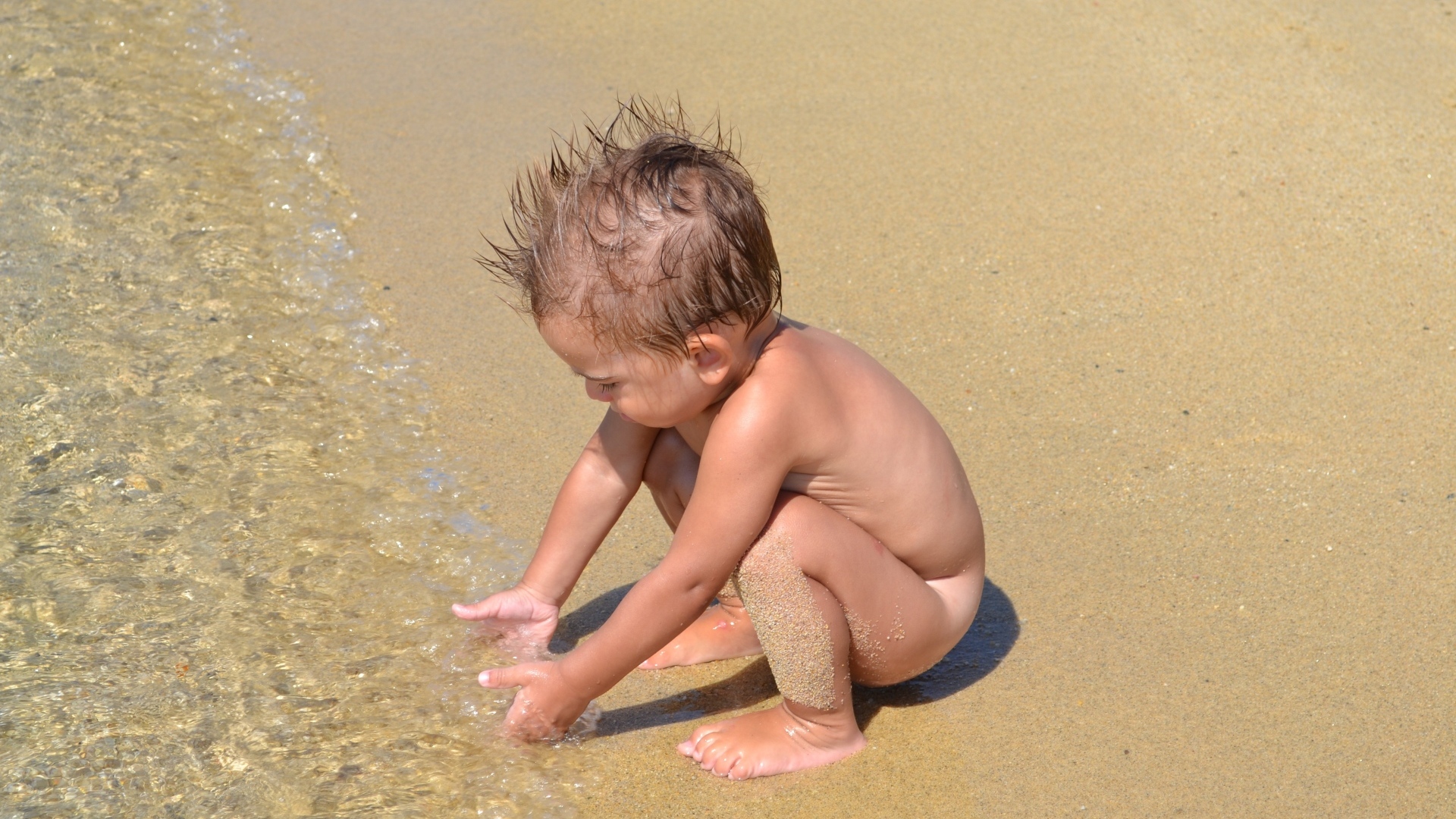 Маленький мальчик на пляже у моря на песке