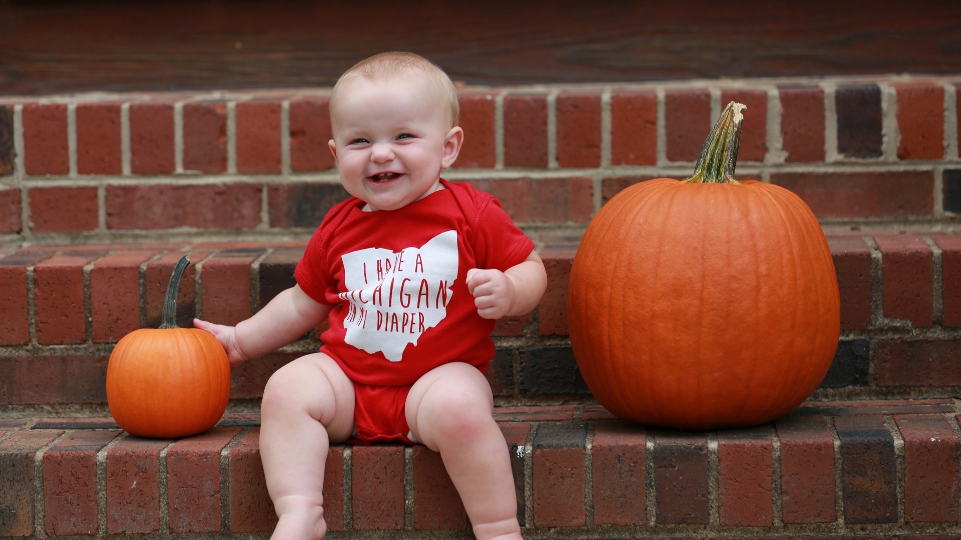 Маленький улыбающийся ребенок с тыквами на ступенях