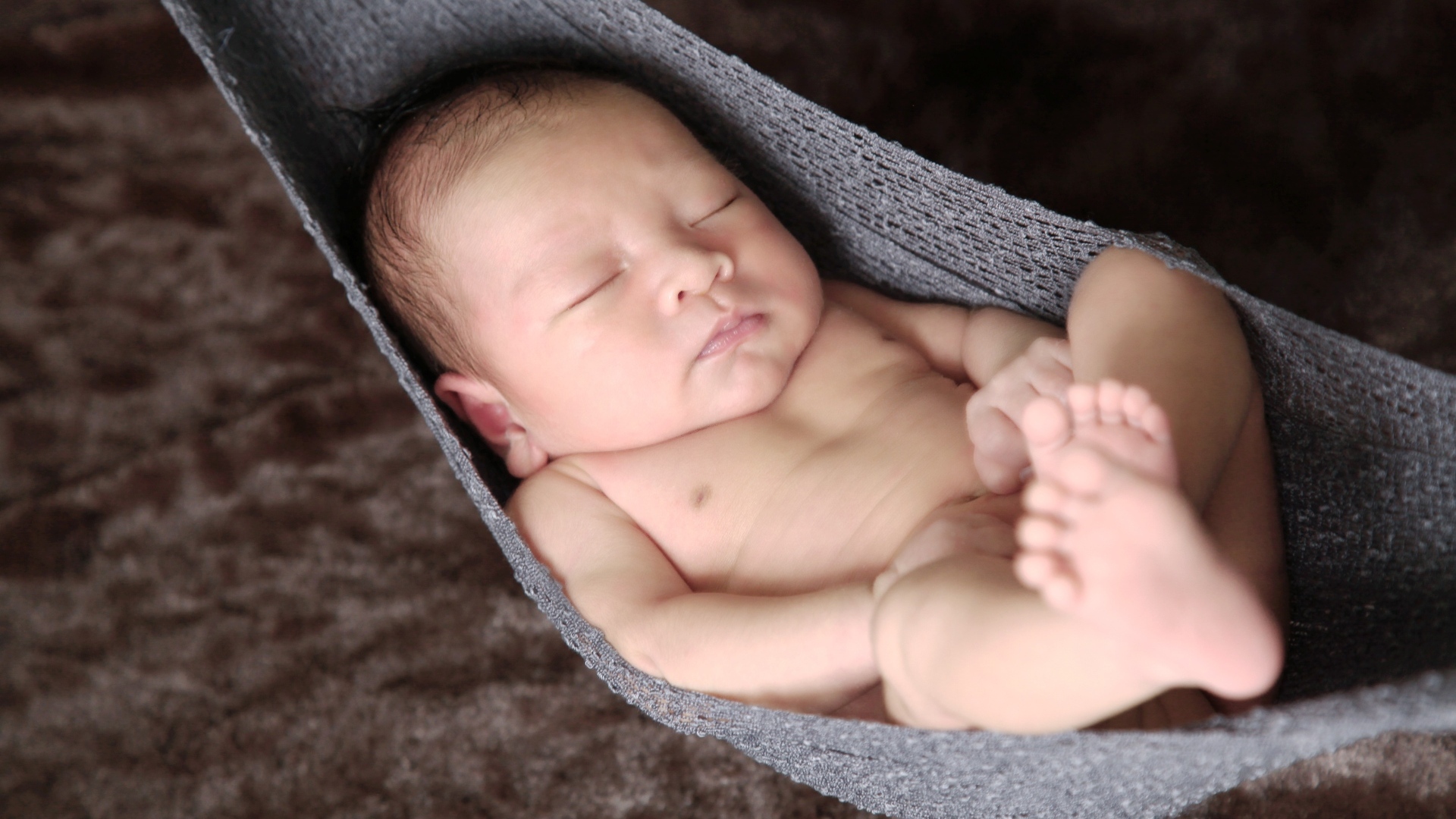 Новорожденный спящий малыш в вязаном гамаке