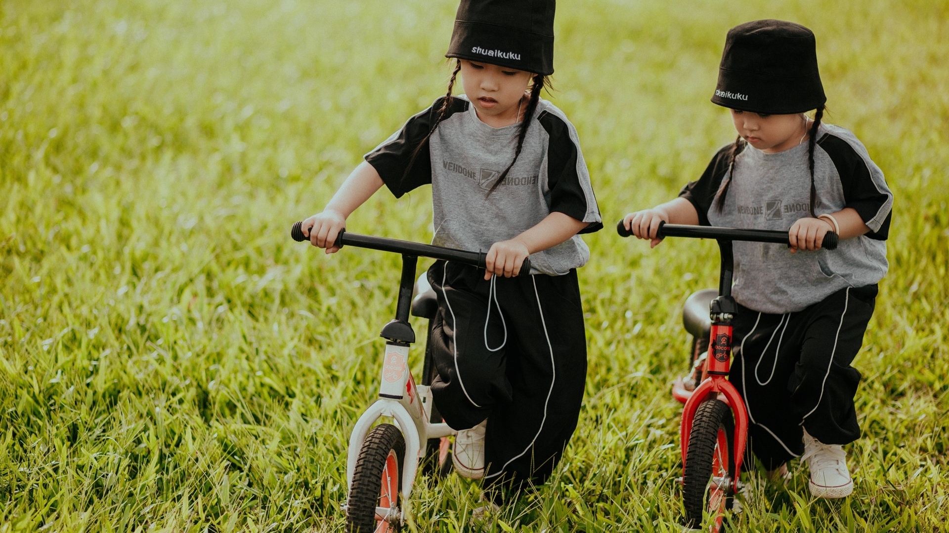 Две девочки с велосипедами на зеленой траве