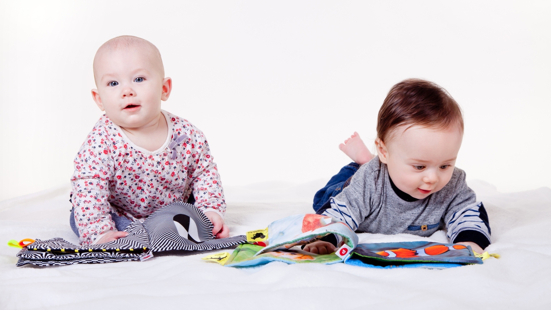 Два маленьких ребенка на кровати с мягкими книгами