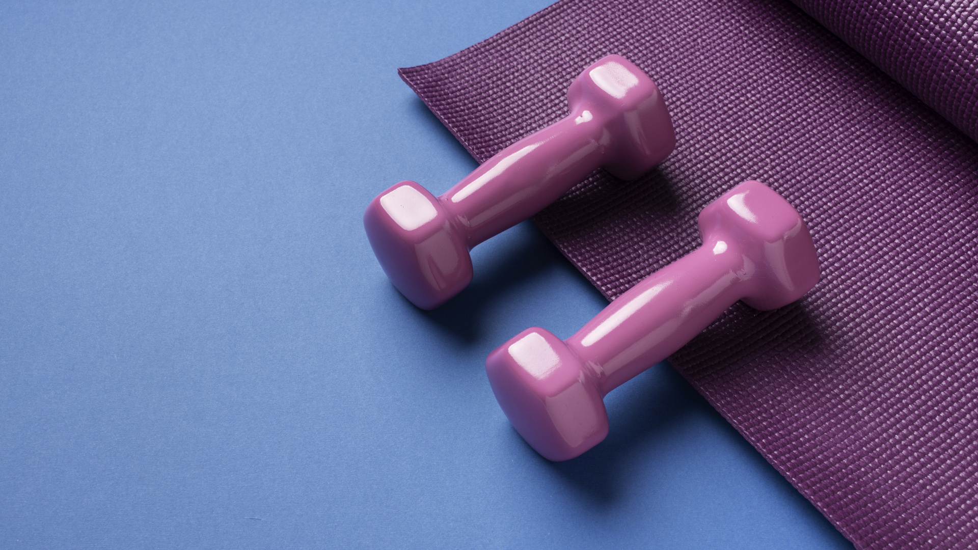 Розовые гантели и коврик на голубом фоне