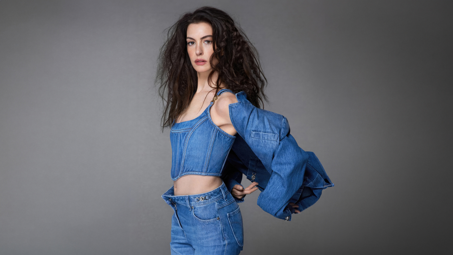 Актриса Энн Хэтэуэй в джинсовом костюме на сером фоне