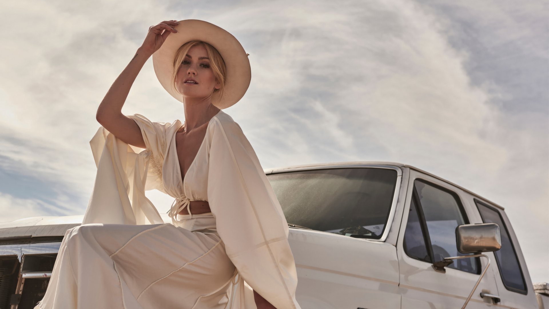 Актриса Кэтрин Макнамара в белом костюме сидит на автомобиле