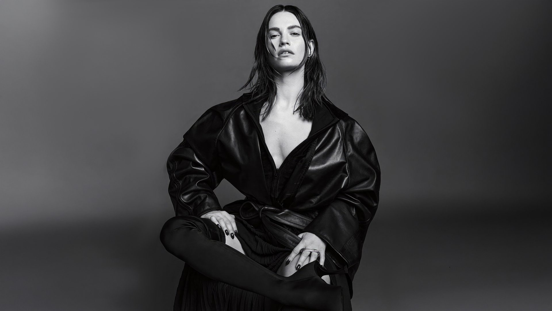 Актриса Лили Джеймс в черном наряде на сером фоне