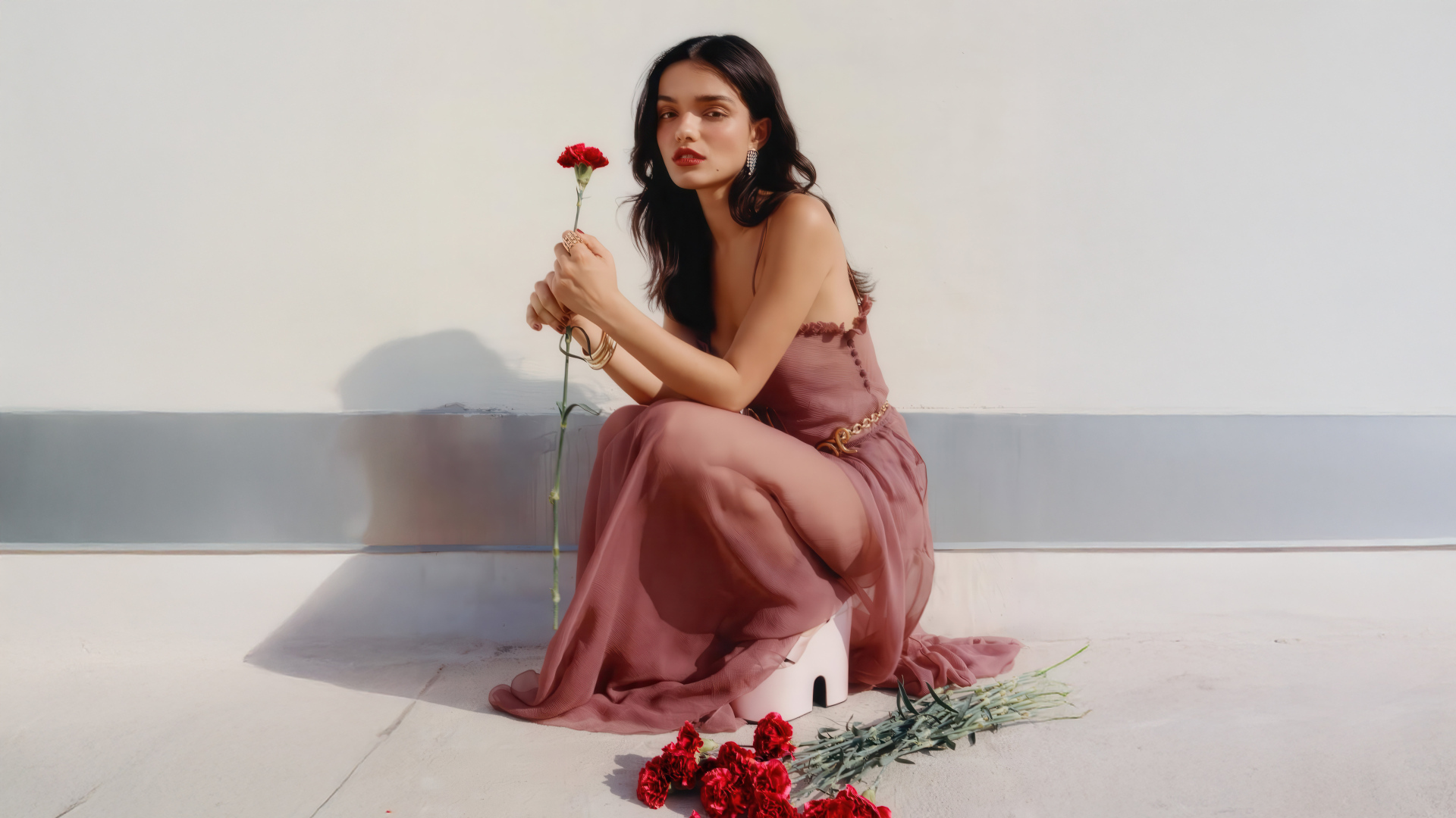 Актриса Рэйчел Зеглер с красными гвоздиками сидит на полу