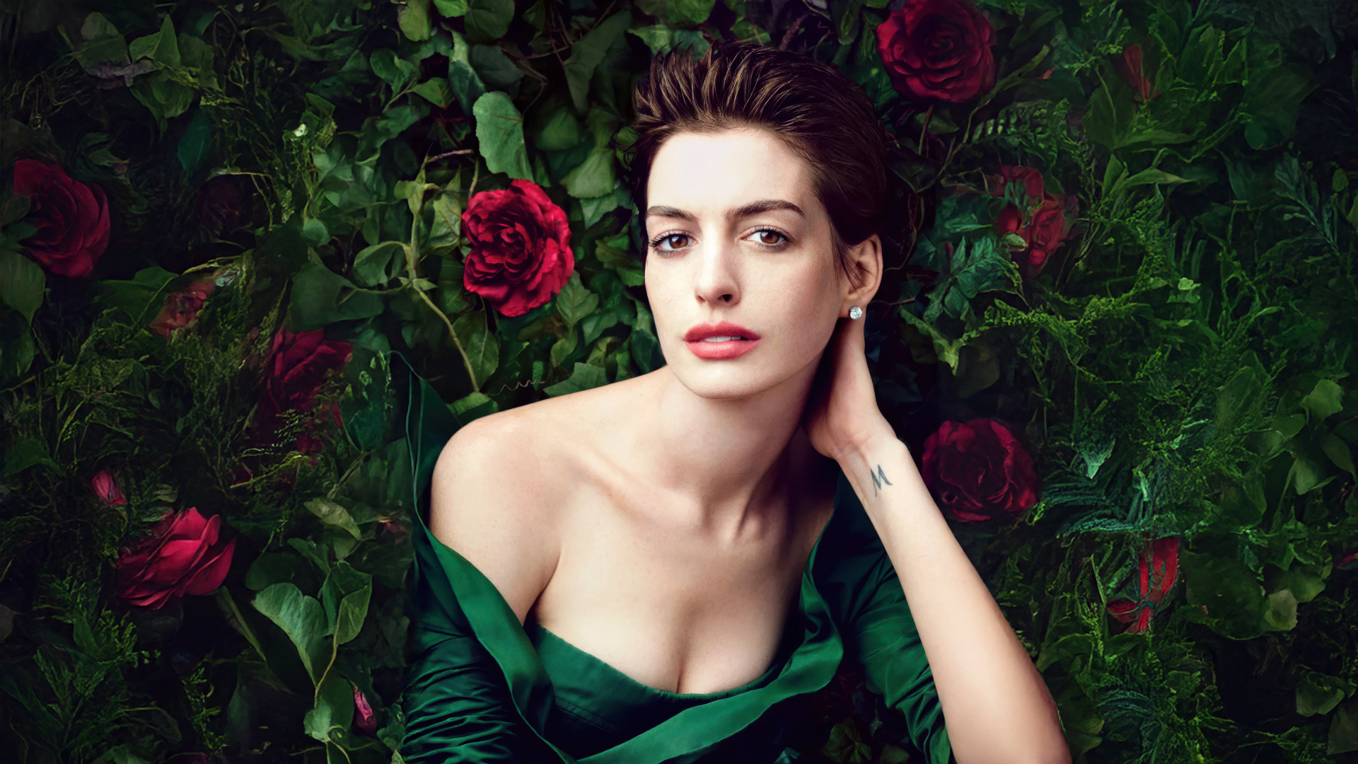 Красивая актриса Энн Хэтэуэй в зеленом платье на фоне роз