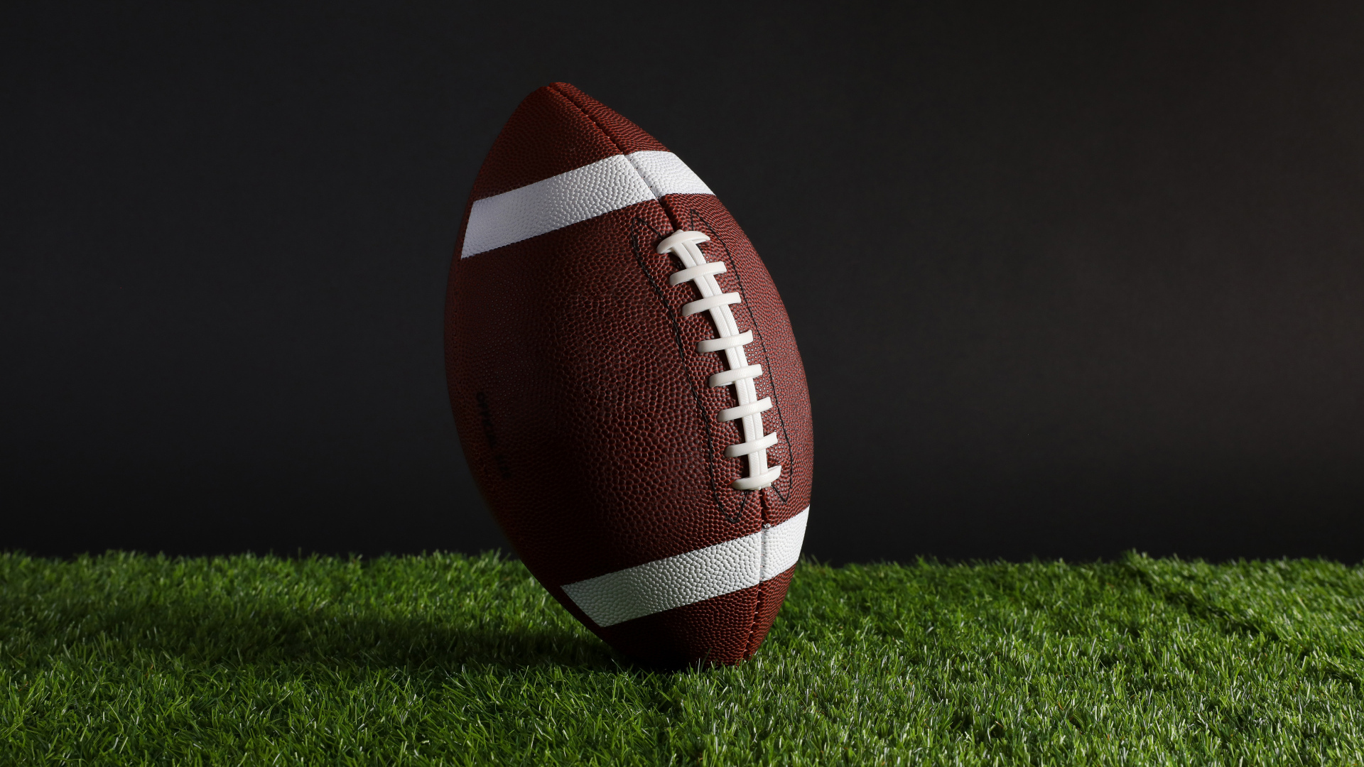 Новый кожаный мяч для американского футбола на траве