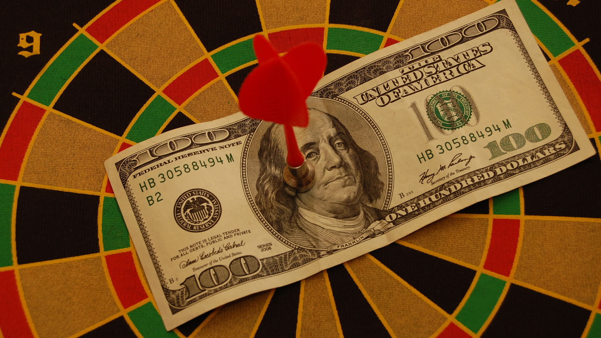 Купюра сто долларов на доске для дартс