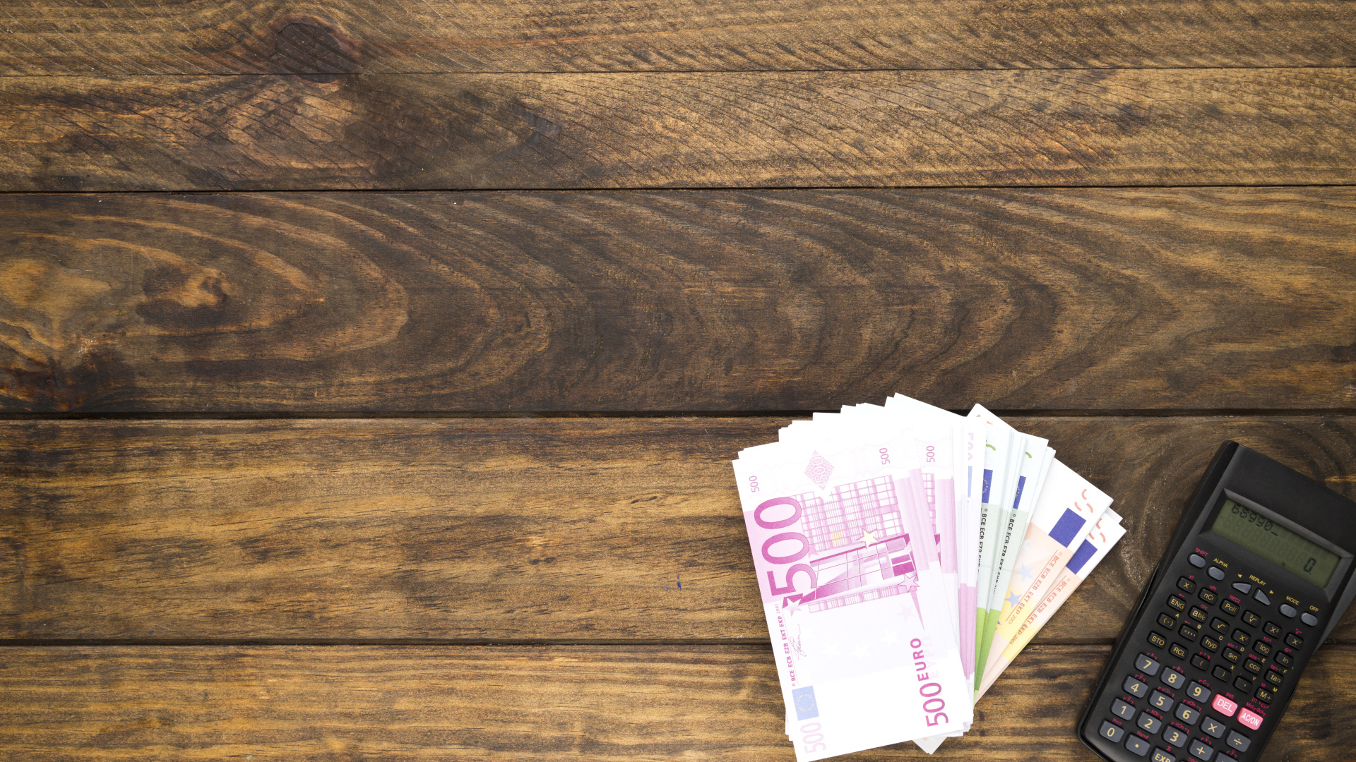 Купюры и калькулятор на деревянном фоне