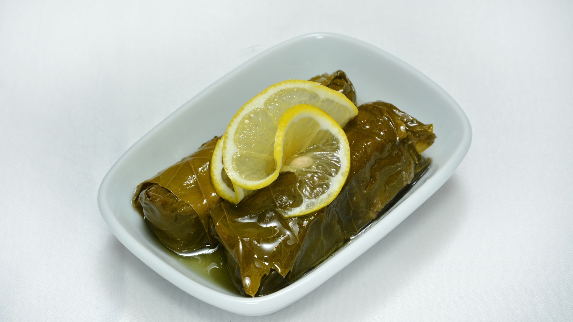 Долма с лимоном с тарелке на сером фоне