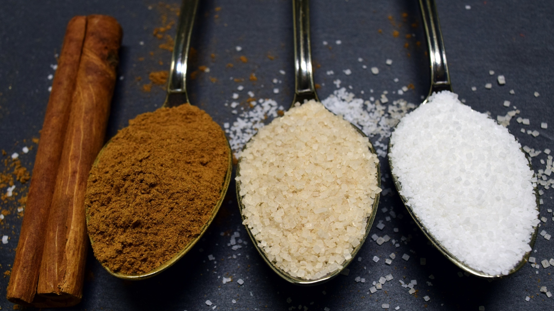 Три ложки со специями на сером столе