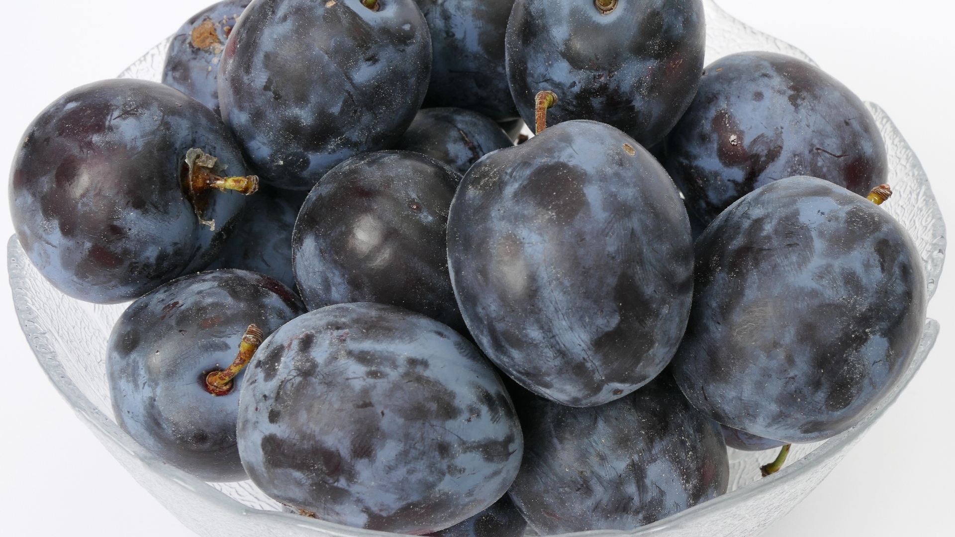 Стеклянная тарелка с вкусными синими сливами