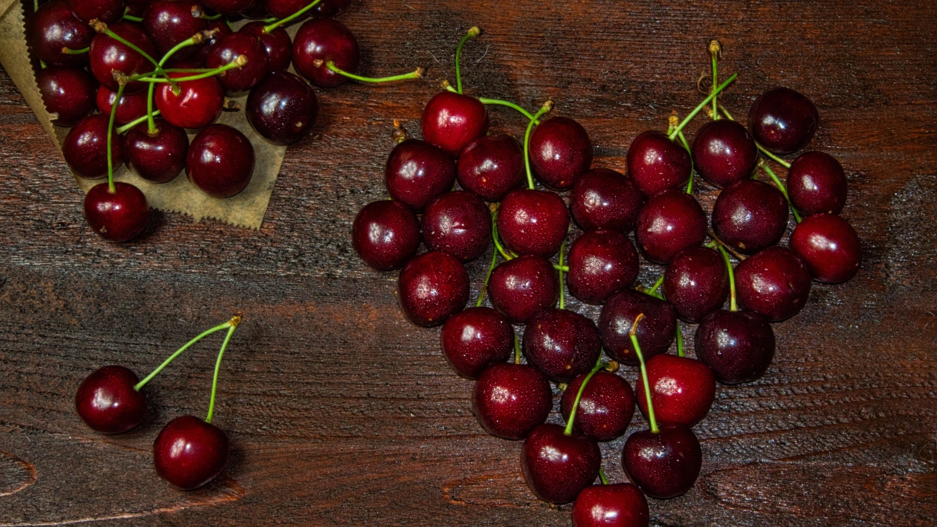 Сердце из спелых ягод черешни на деревянном столе