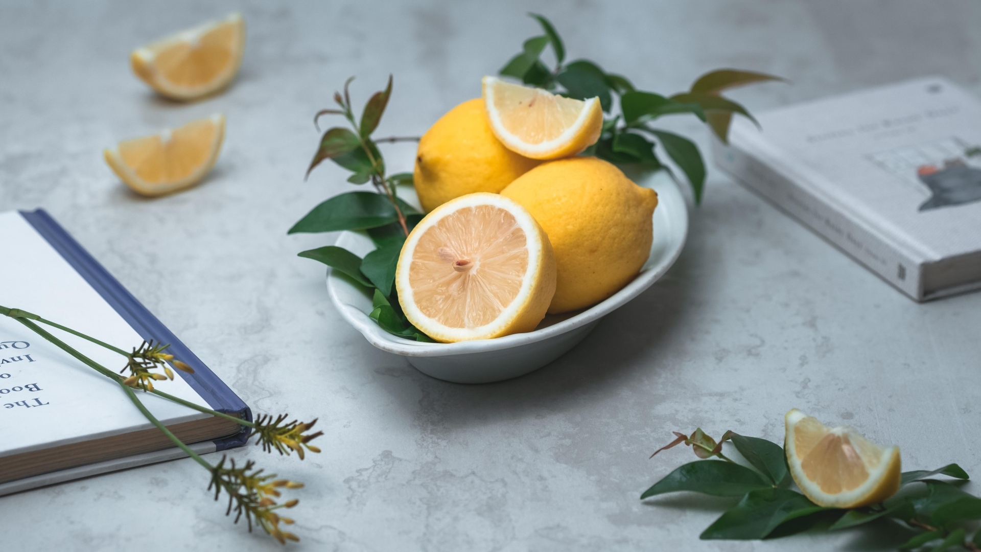 Лимон с зелеными листьями на столе с книгами