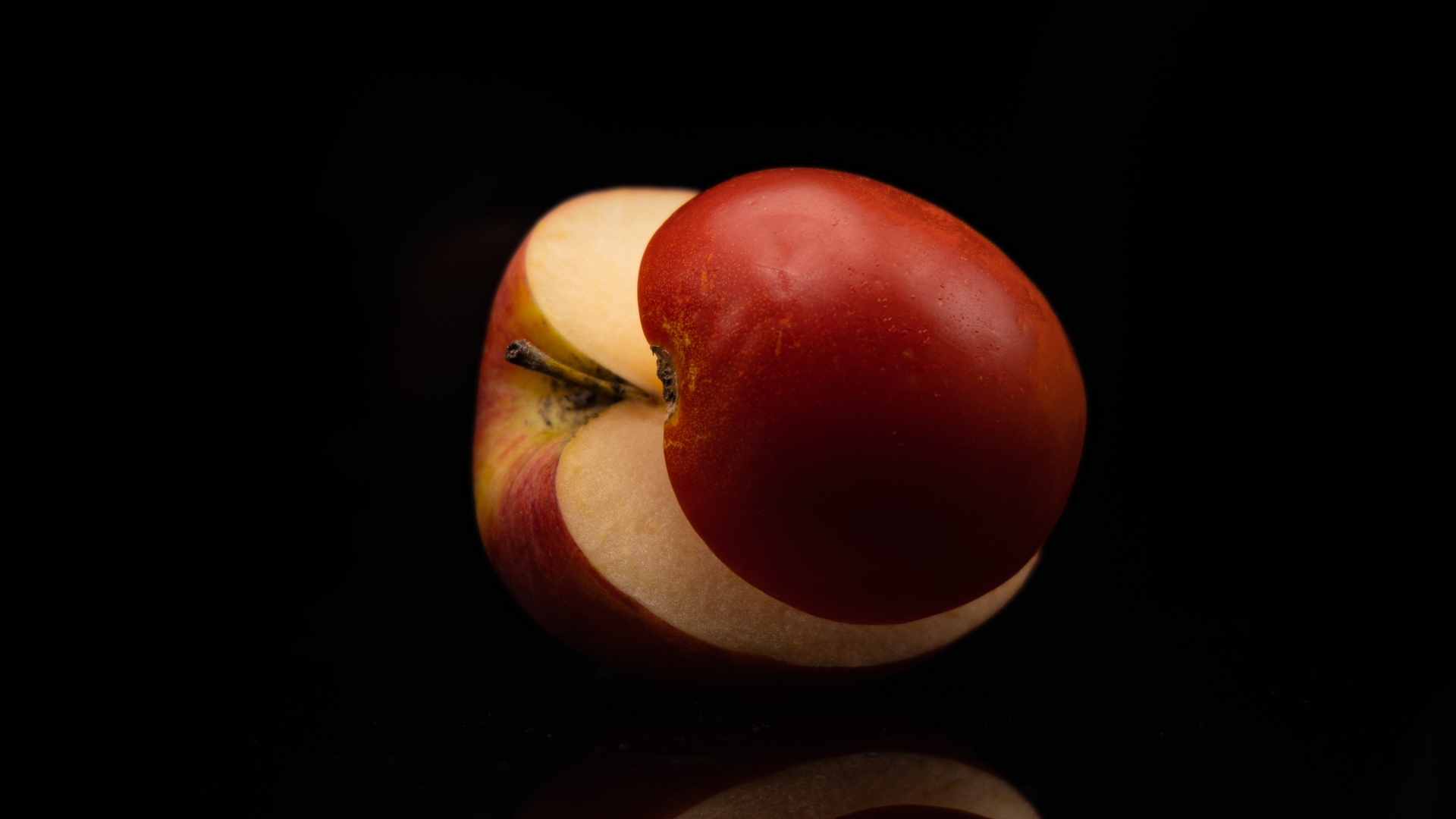 Разрезанное на половинки красное яблоко на черном фоне