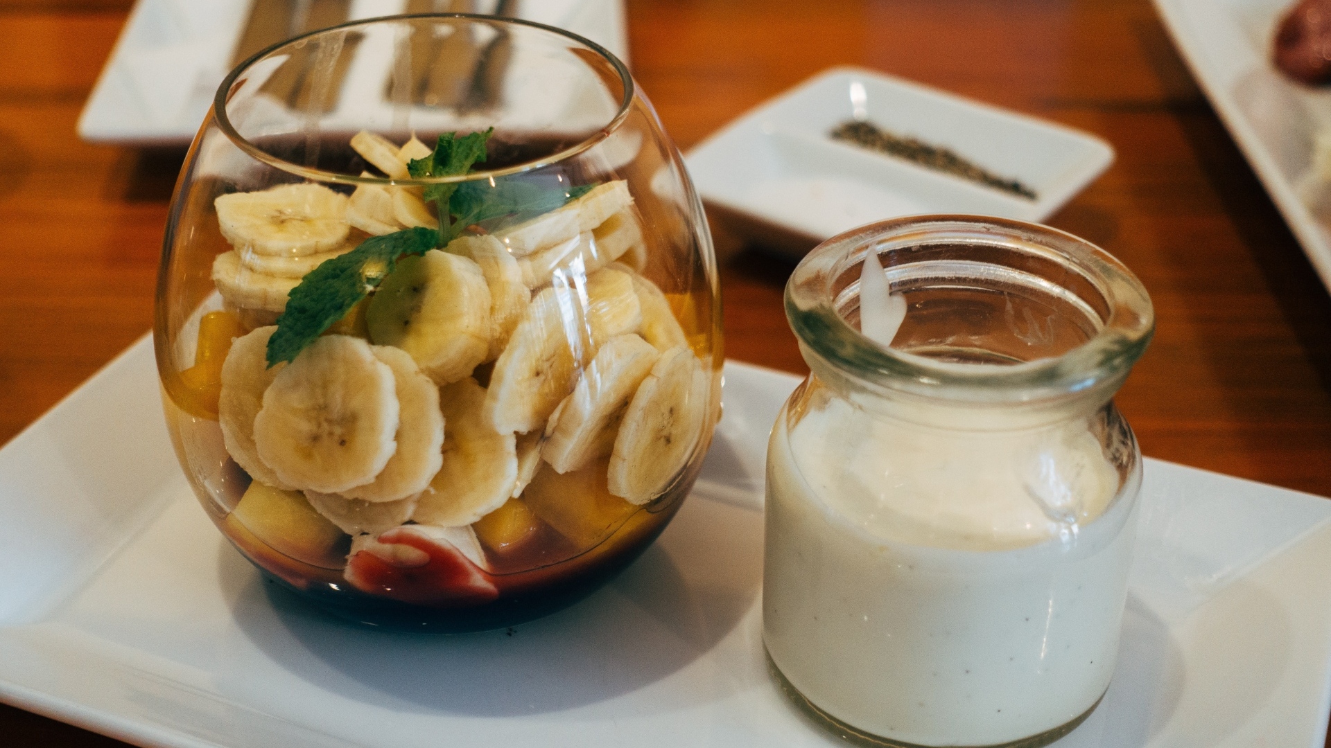 Нарезанные бананы в стакане на столе с йогуртом