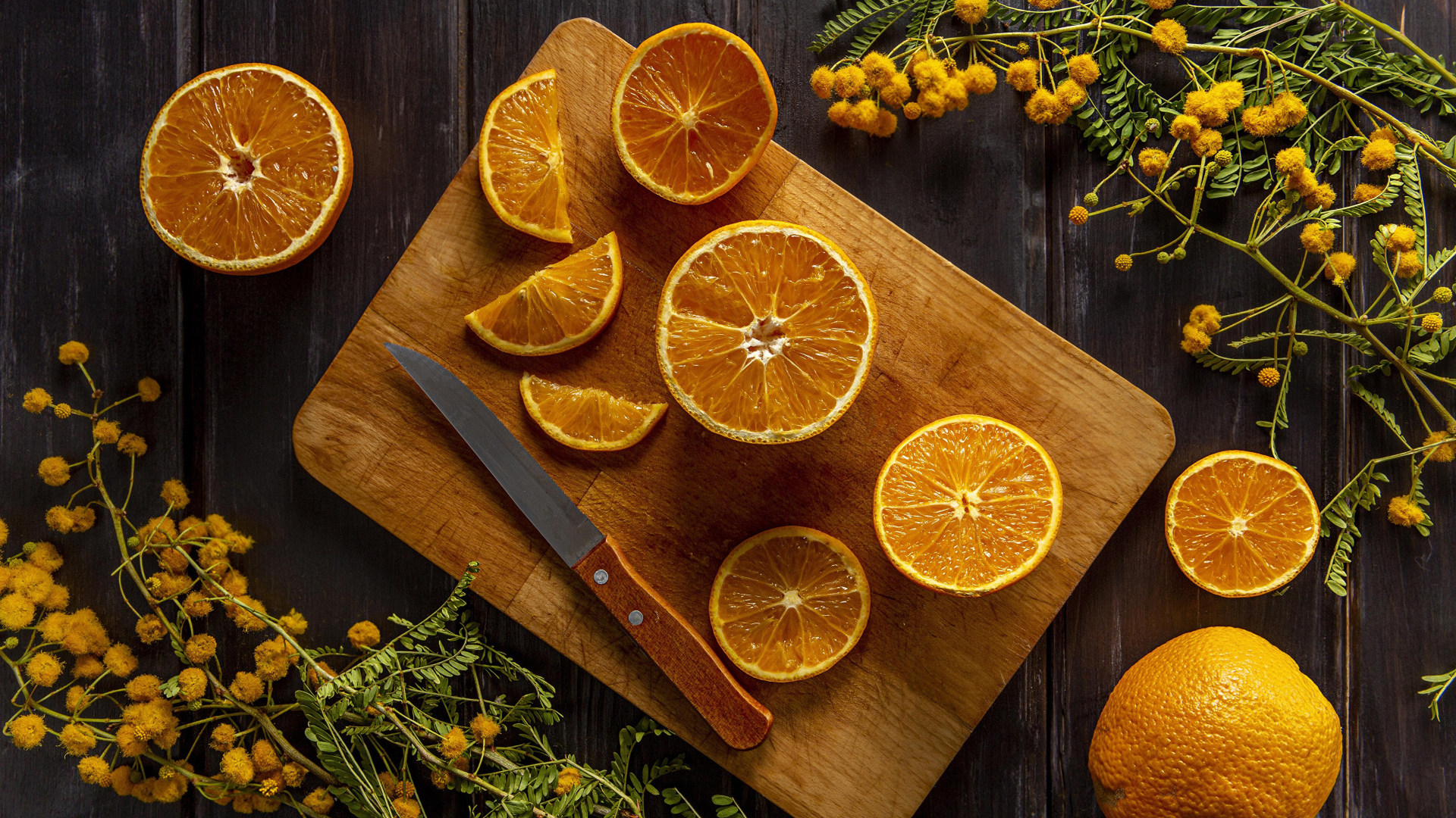 Нарезанный апельсин на доске на столе с цветами