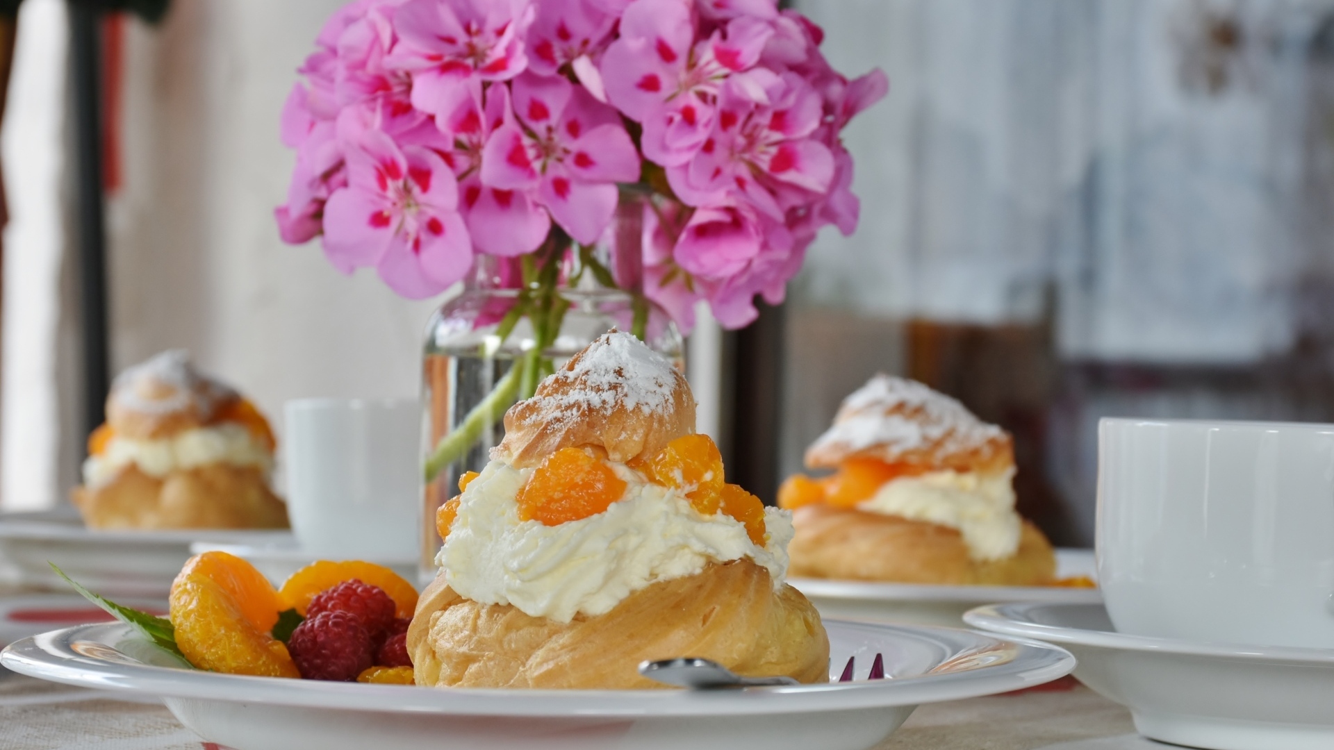 Булочки с кремом и фруктами на столе с букетом