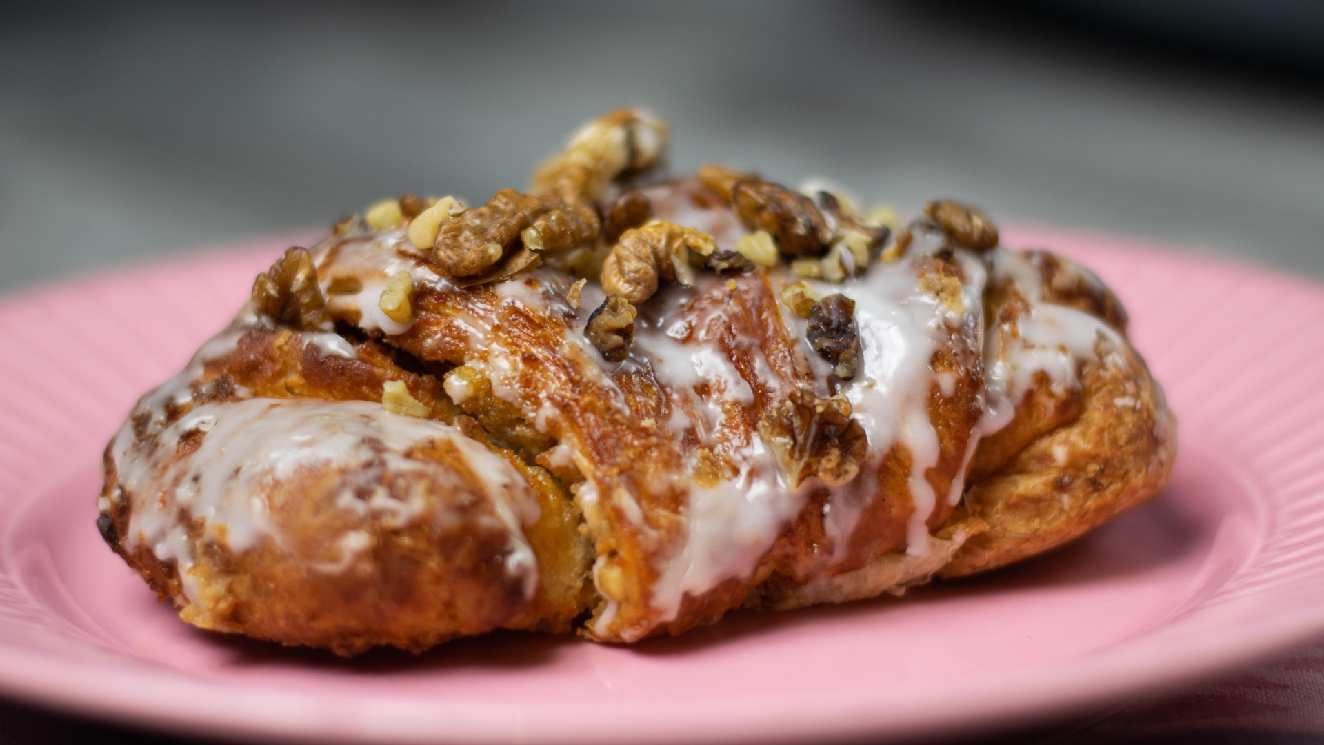 Круассан с кремом и грецкими орехами на розовой тарелке