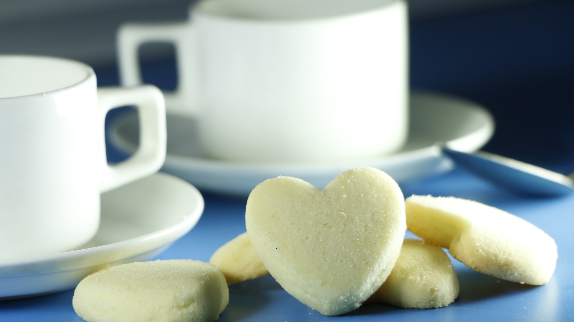 Сладкое печенье в форме сердца с кружками на столе