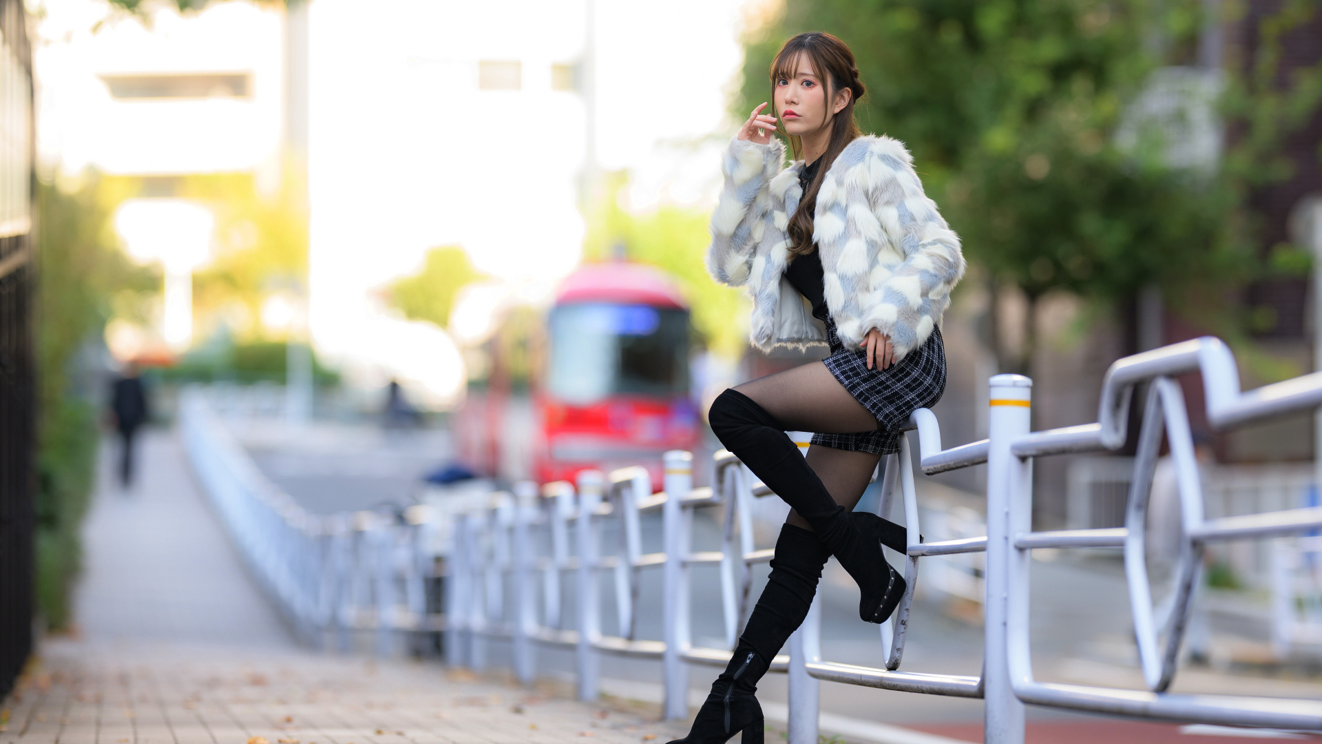 Азиатка в шубе стоит у забора