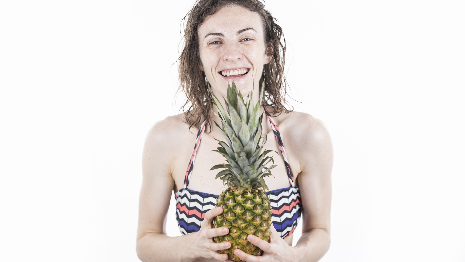 Улыбающаяся девушка с ананасом в руках