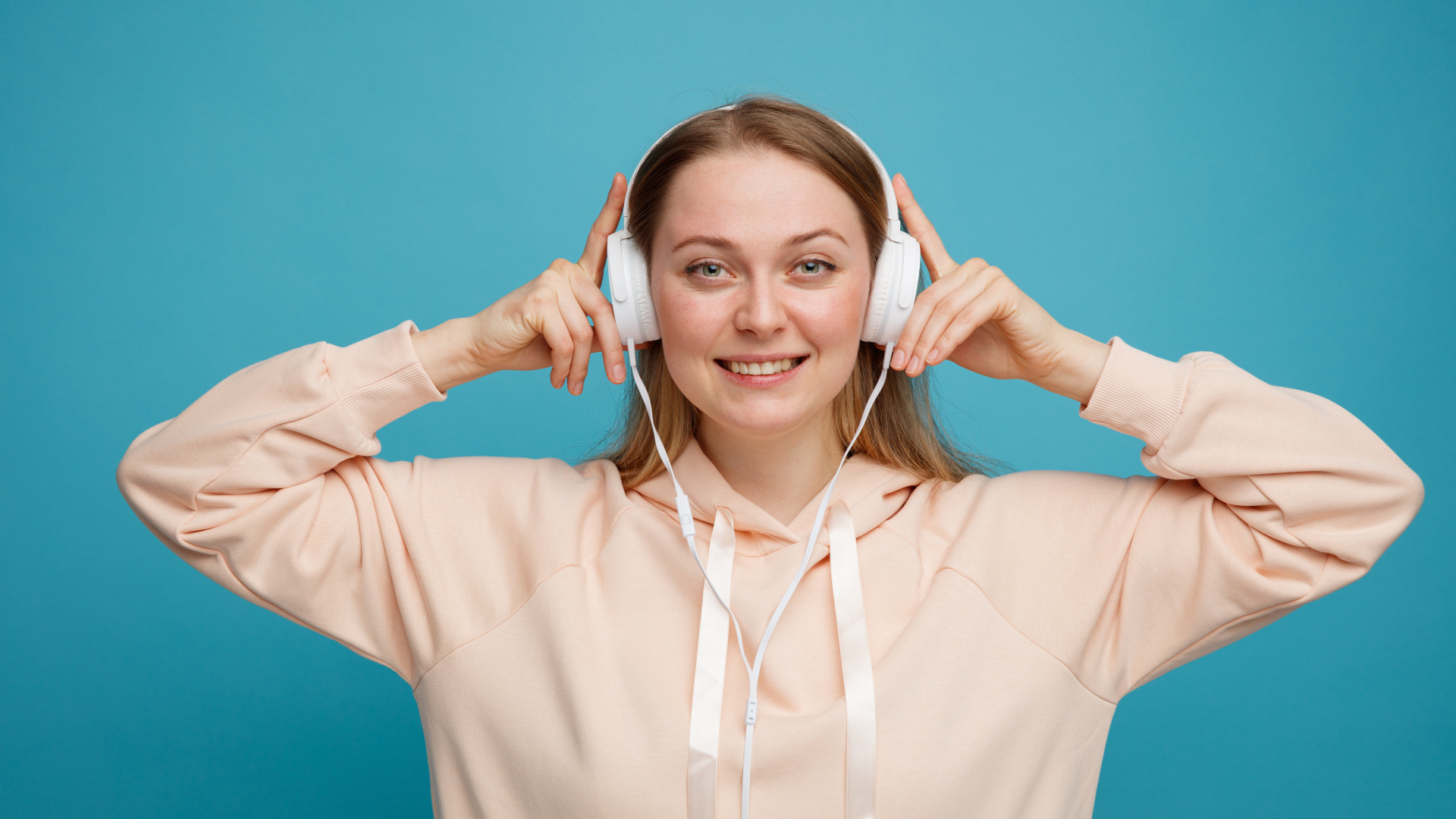 Улыбающаяся девушка в наушниках на голубом фоне