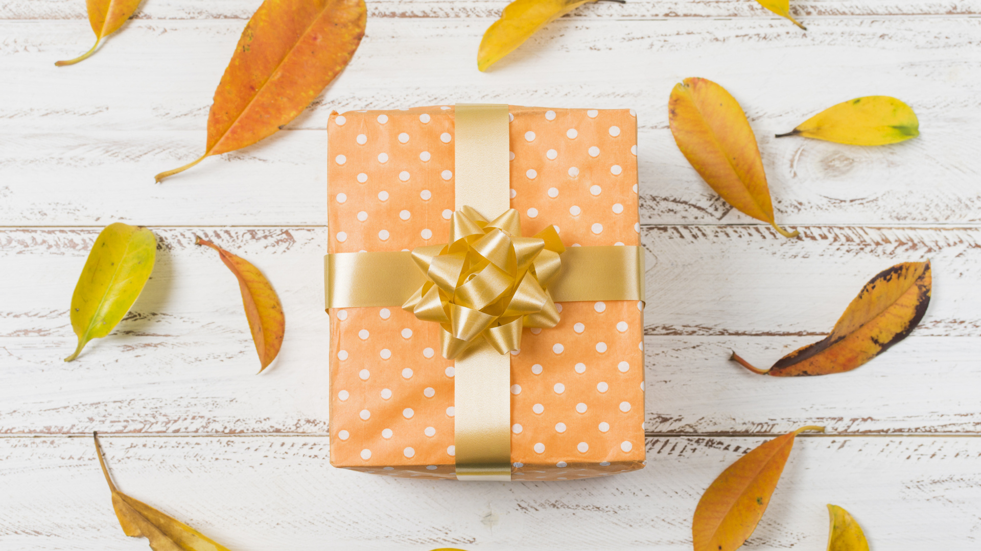 Подарок с желтыми листьями на белом фоне