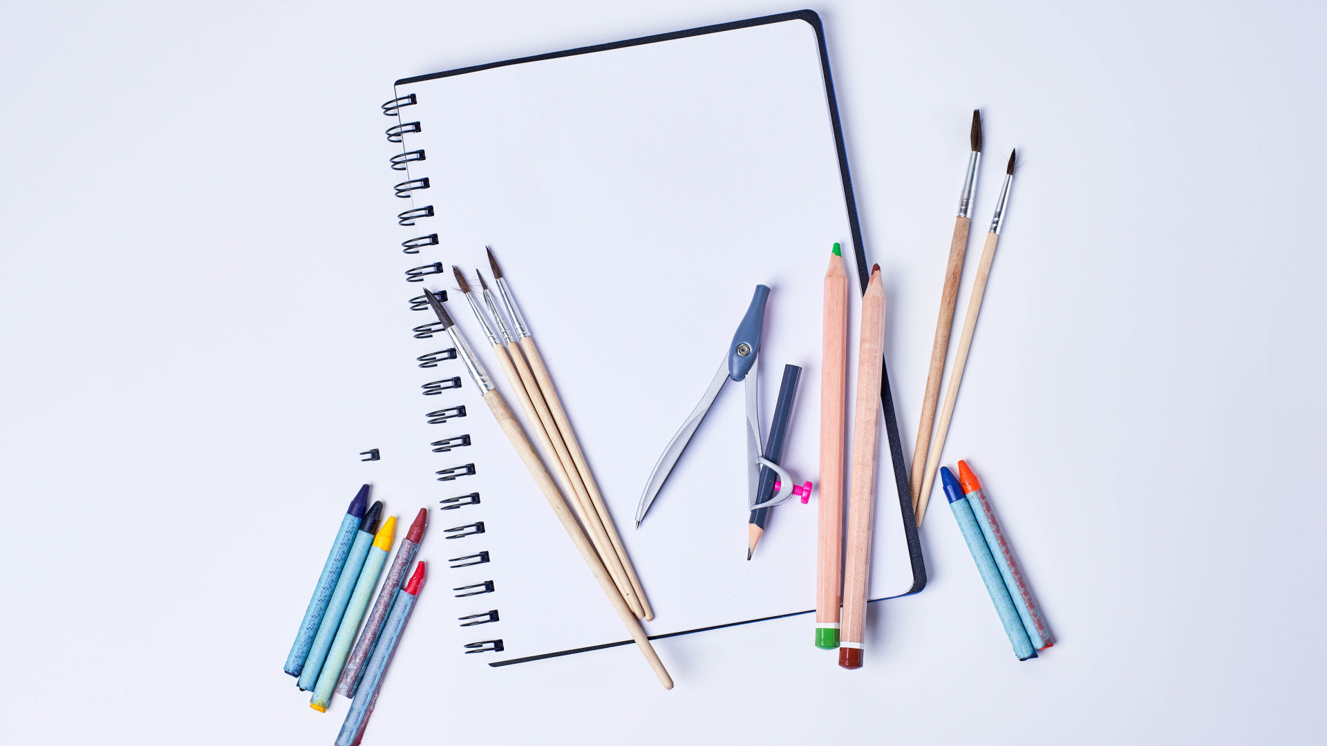 Карандаши, кисти и блокнот для рисования на сером фоне