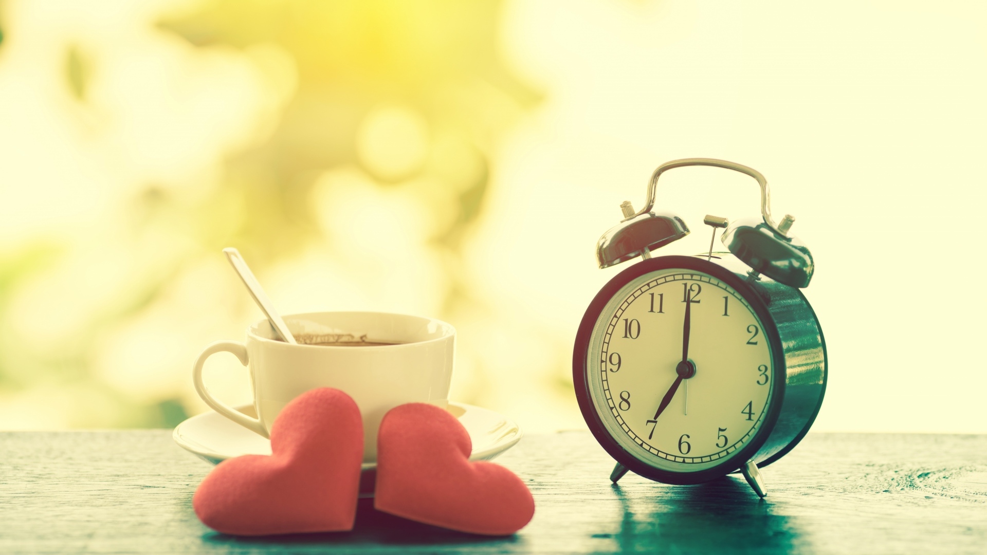 Будильник на столе с чашкой кофе и сердечками