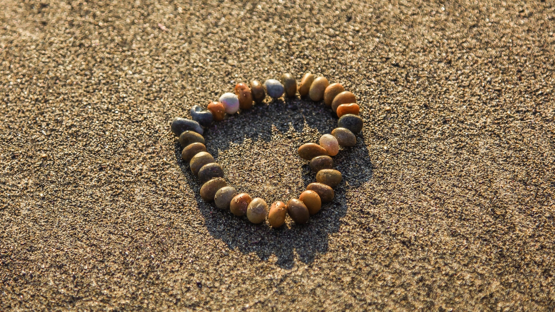 Сердце из камней на морском песке летом